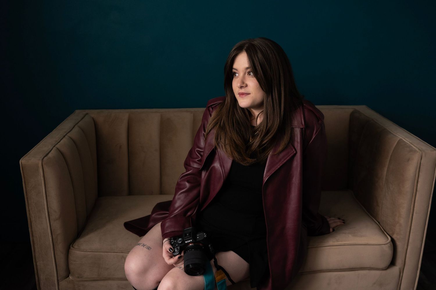 Utah photographer seated on couch holding camera during personal branding session