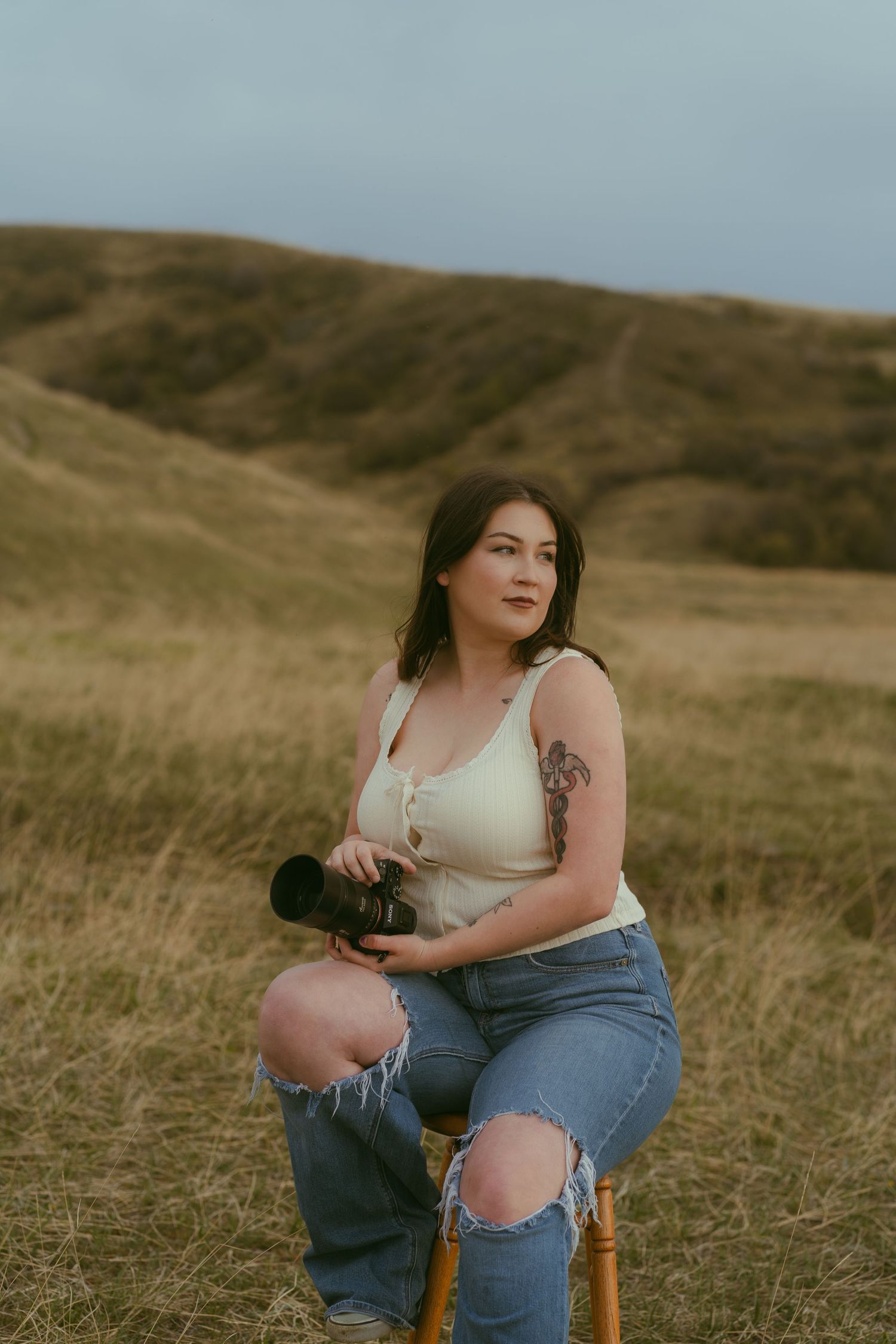 Utah photographer seated in field holding camera during branding session