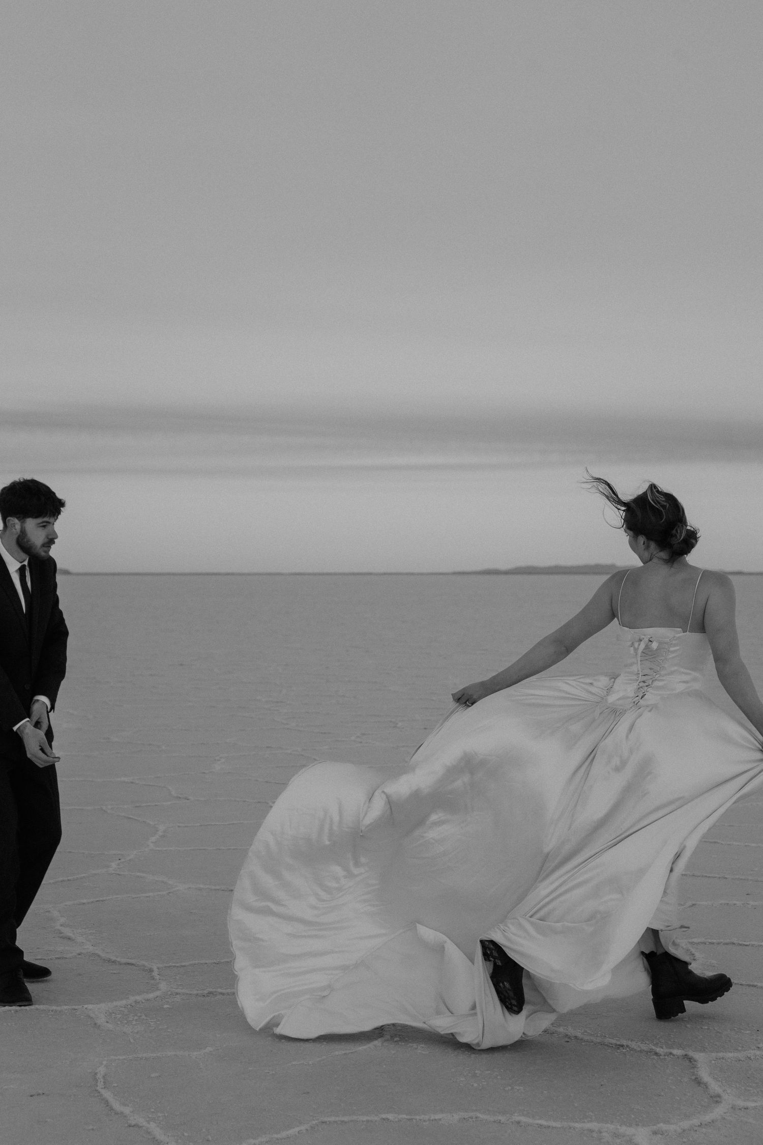 Black and white bridal photo of bride twirling dress at Bonneville Salt Flats