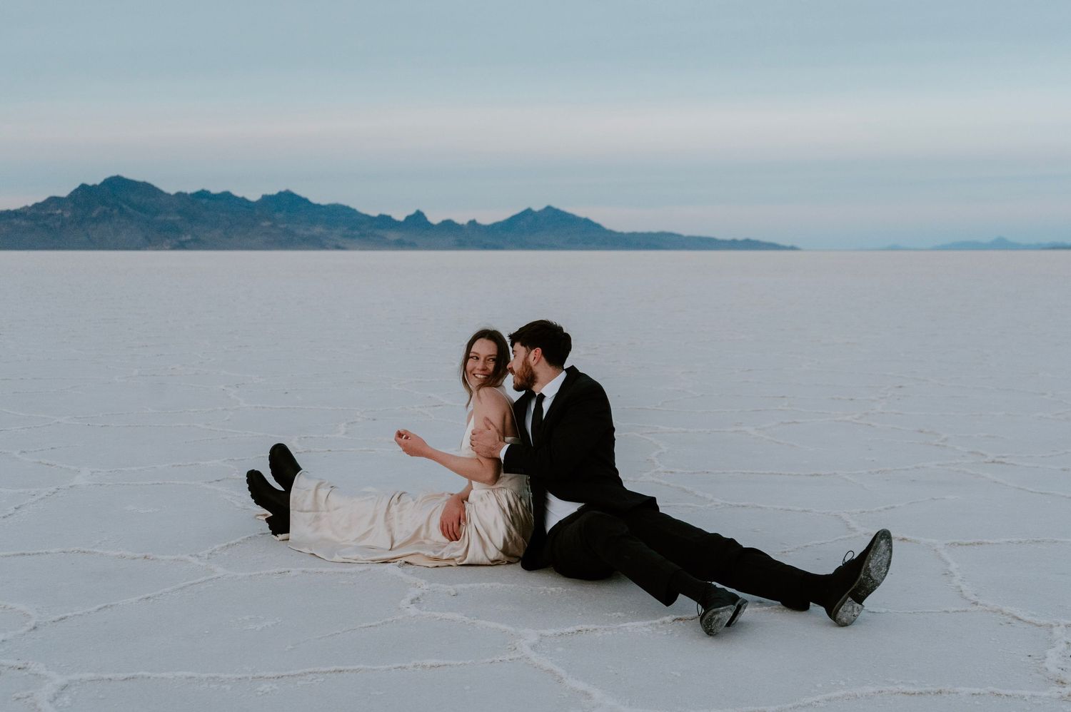 Bride and groom sitting together during romantic Bonneville Salt Flats bridal session
