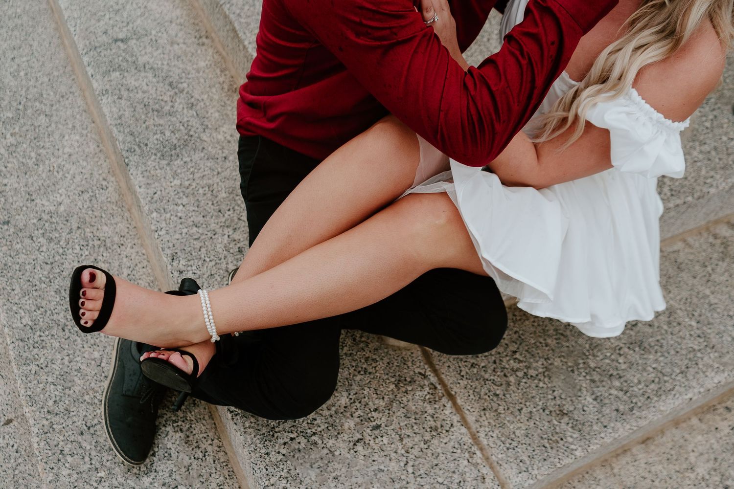 Couple embracing while seated together during playful urban engagement session