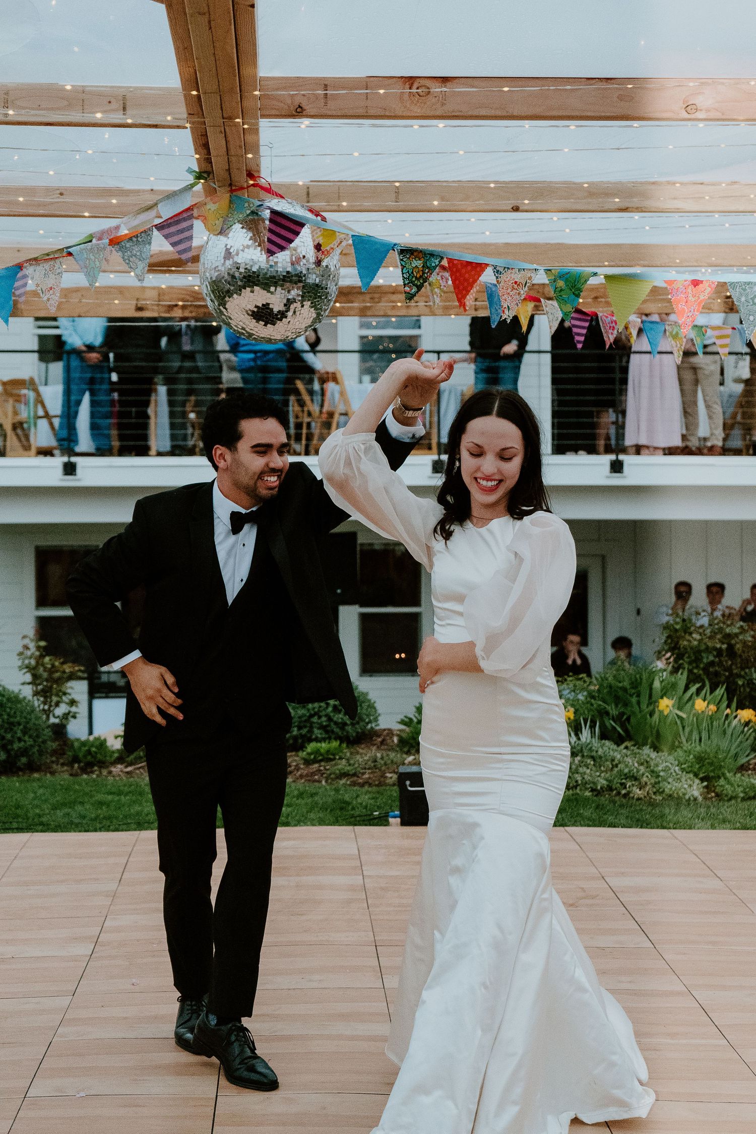 Bride and groom dancing at wedding reception with guests watching