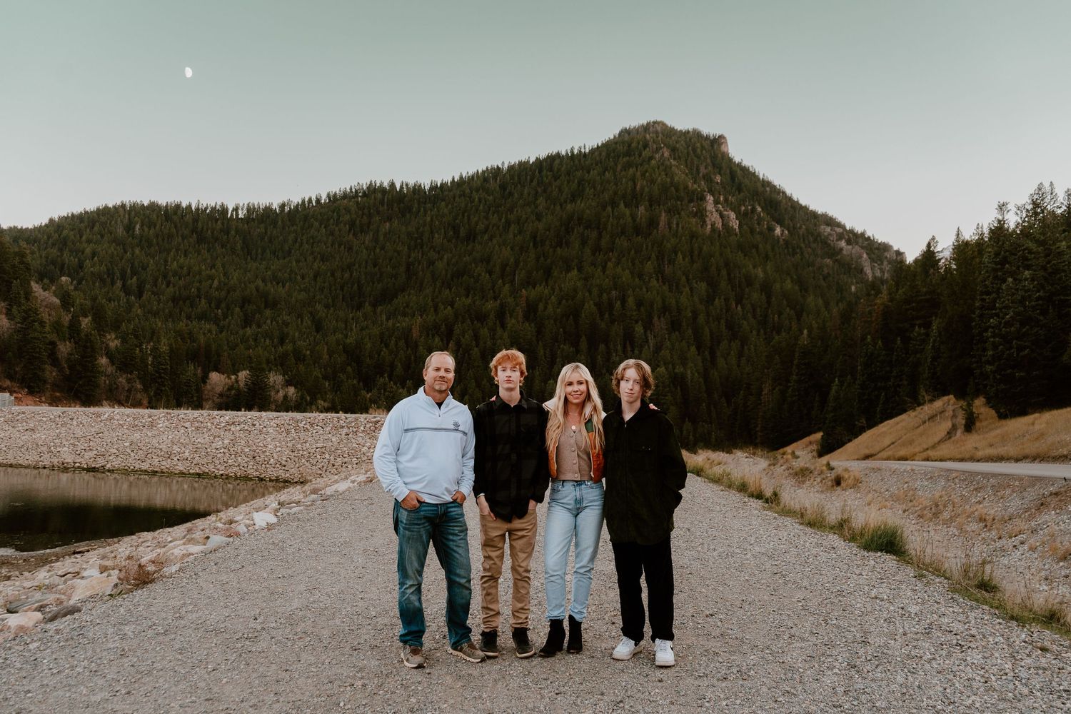 Family of four standing together on mountain road during outdoor portrait session