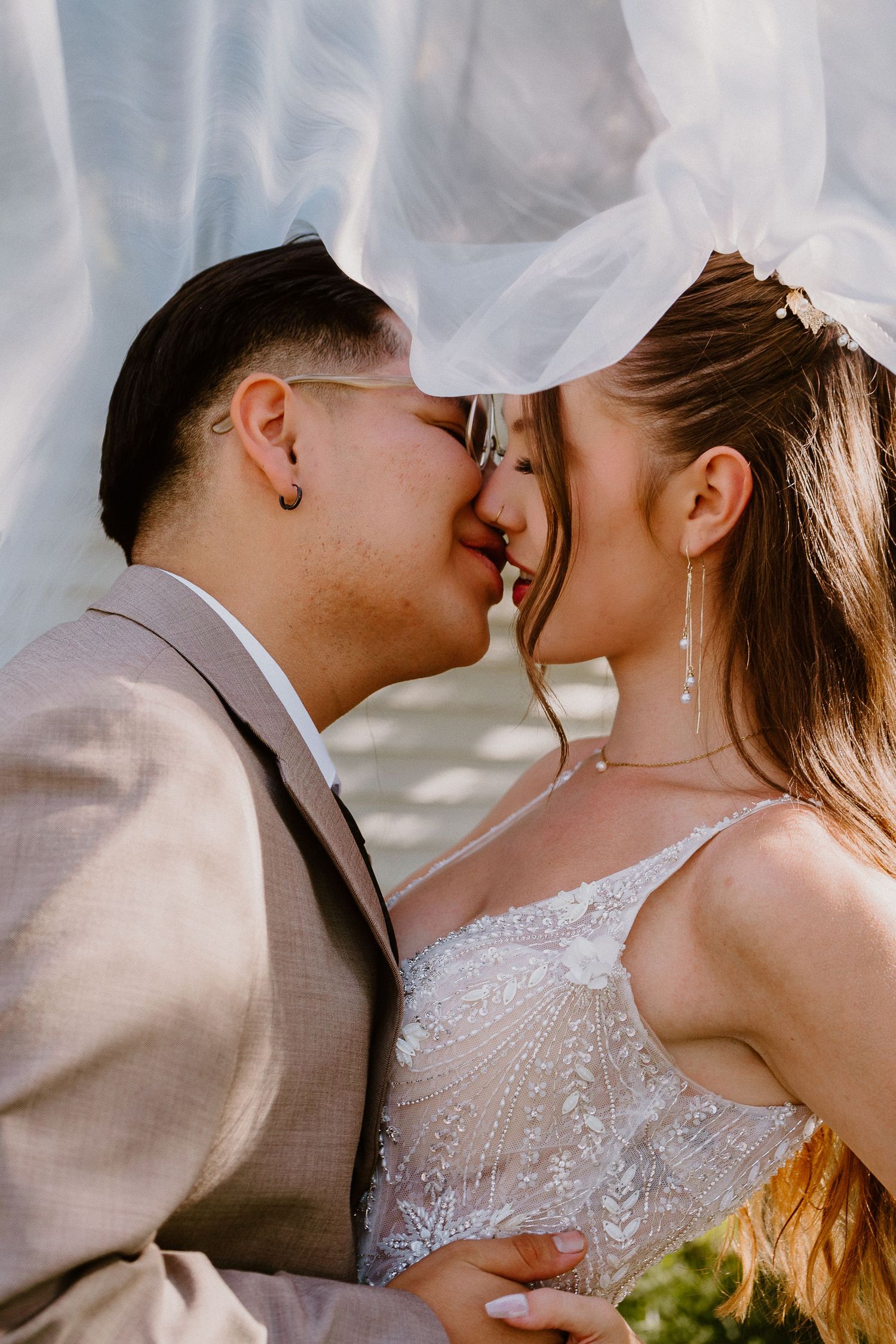 Bride and groom kissing beneath veil during romantic wedding portrait