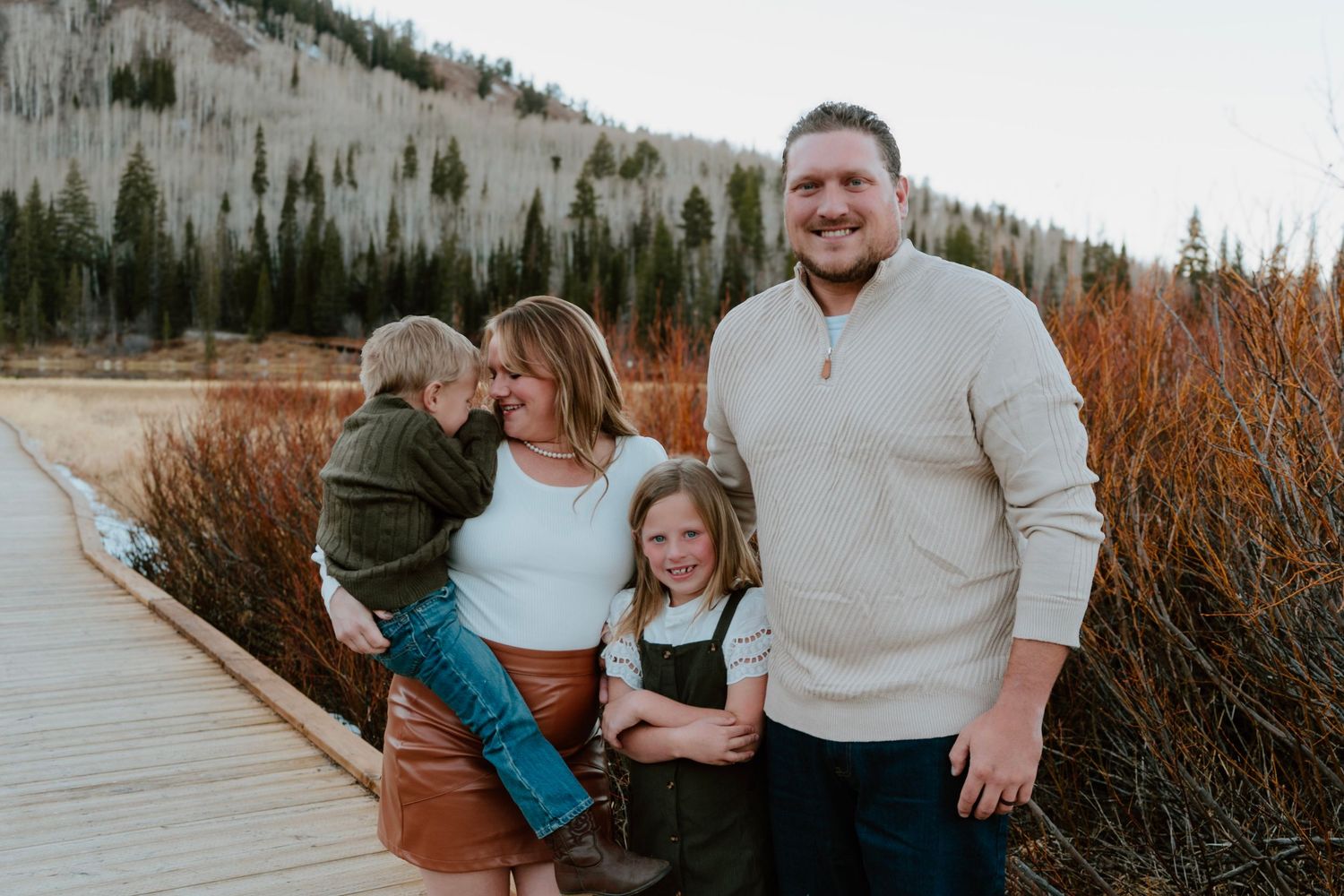 Family of four smiling together during mountain family photo session