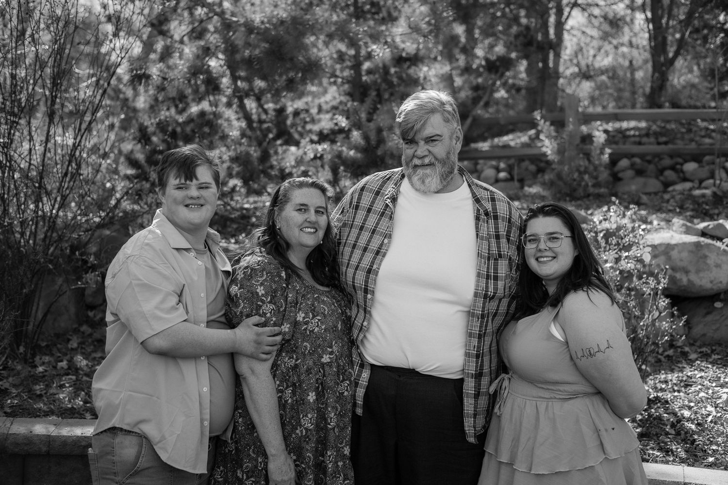 Black and white portrait of a man with three young adult women smiling together in a garden.