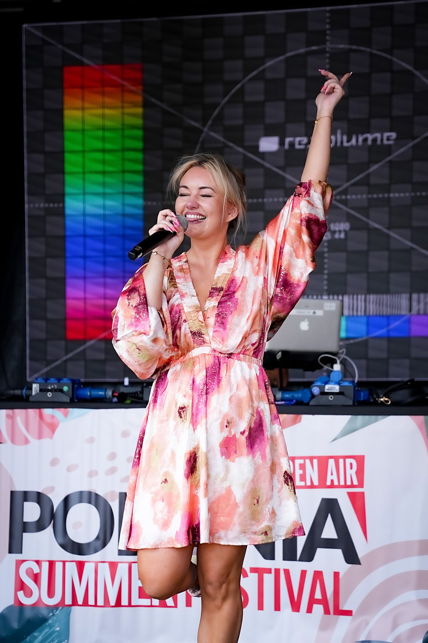 A blonde female singer in a floral dress performs on stage at the Polonia Summer Festival outdoor event.