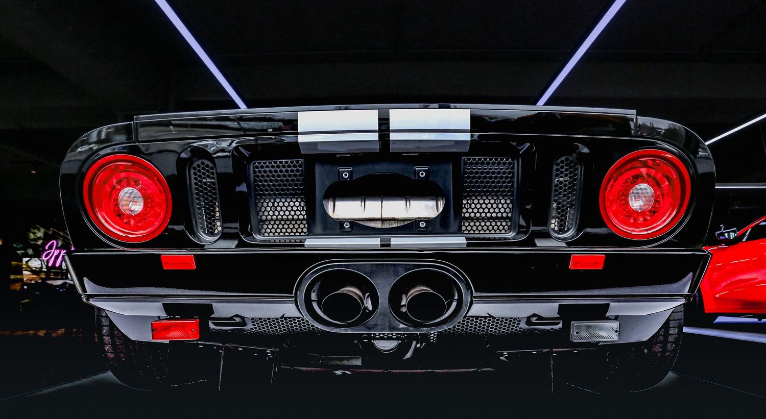 Rear view of a black Ford GT40 with red taillights and dual exhausts.
