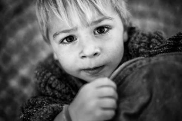 Close-up black and white portrait of a young blonde child with expressive eyes.