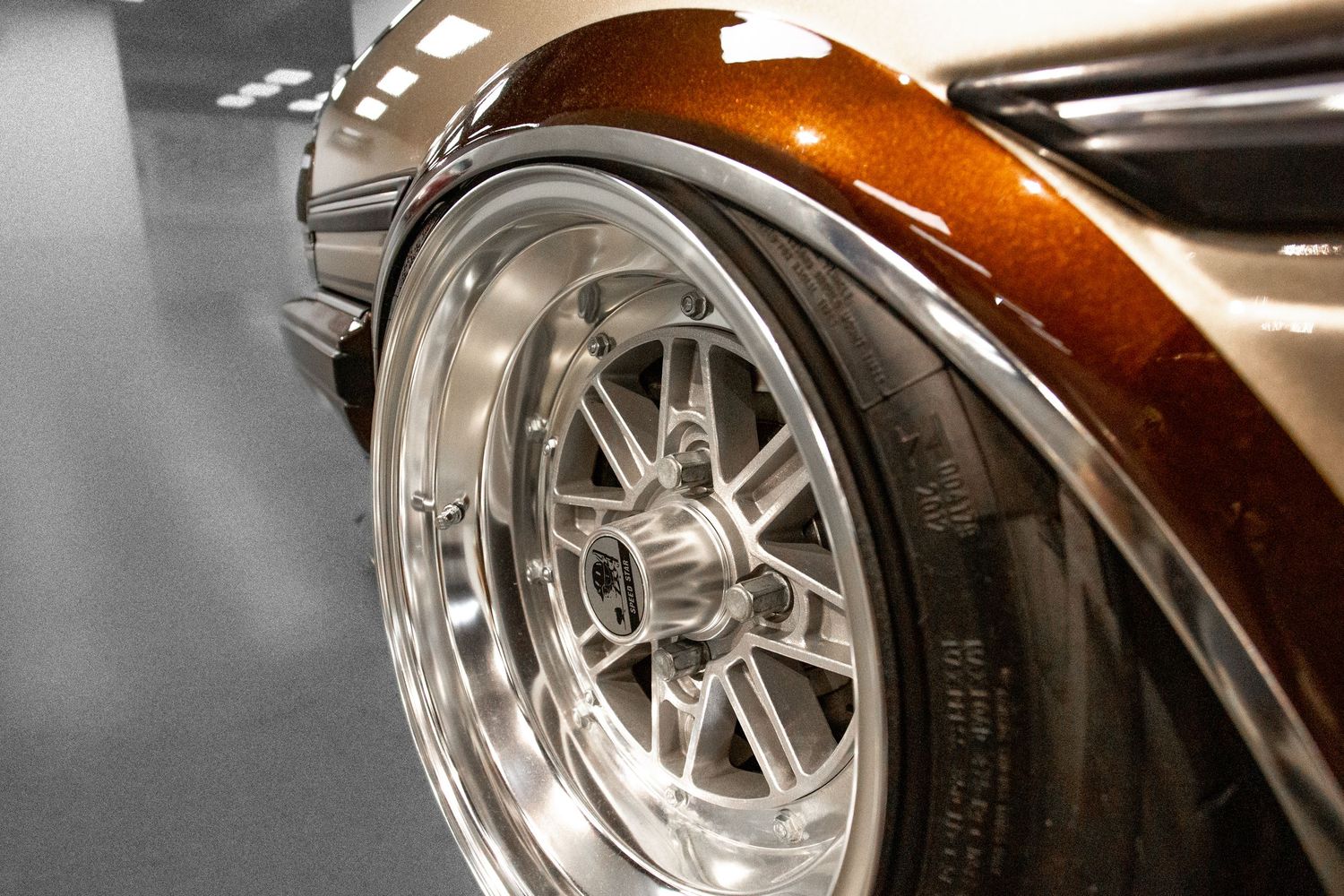 Close-up of a polished chrome wheel on a classic copper metallic car.