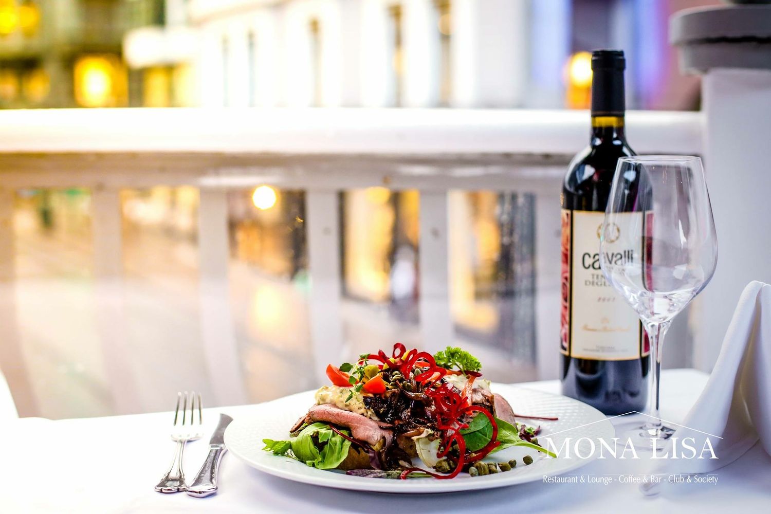 Mona Lisa restaurant elegant salad dish served with a bottle of red wine and empty wine glass.