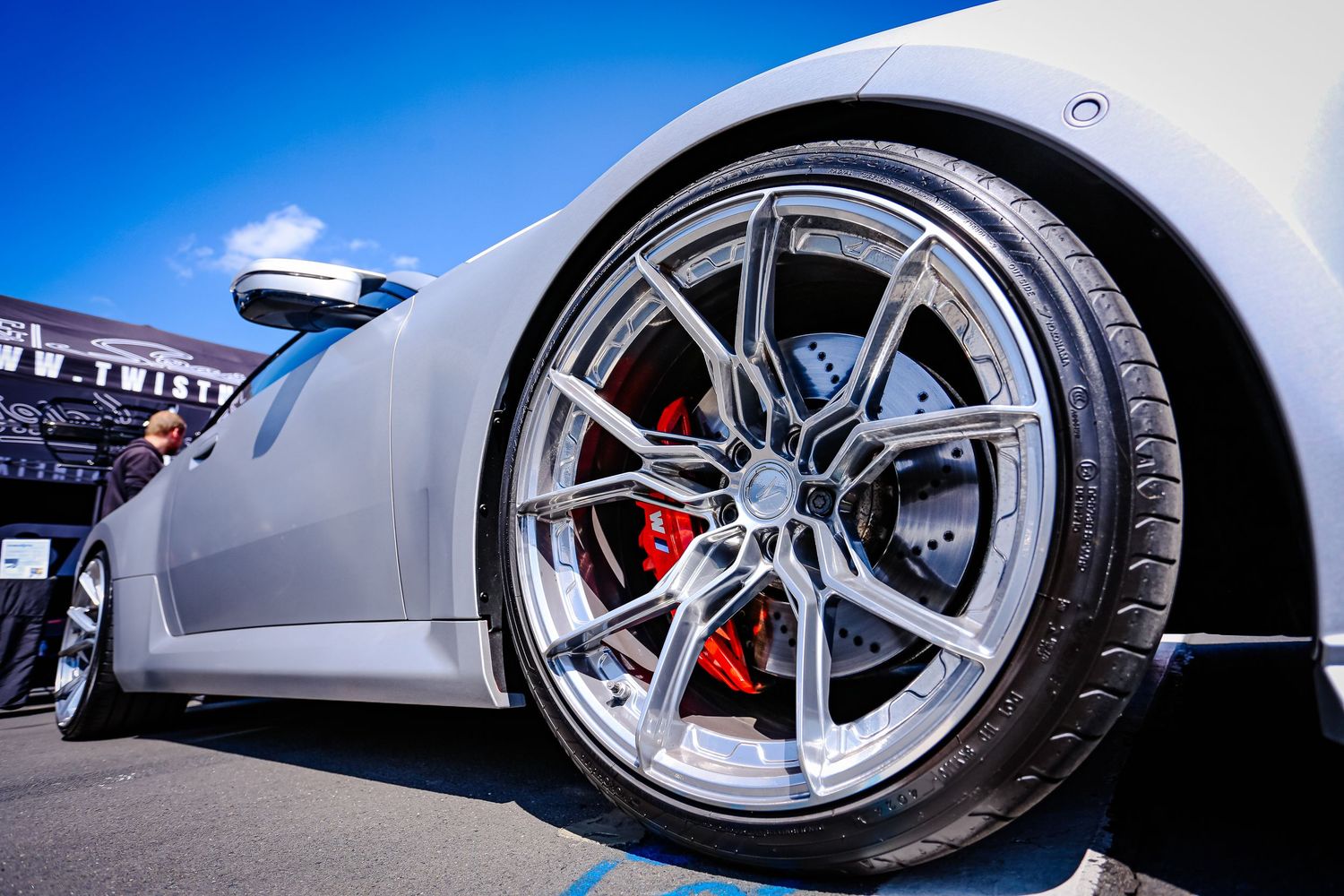Close-up of a white supercar wheel with red brake calipers and silver alloy rims.