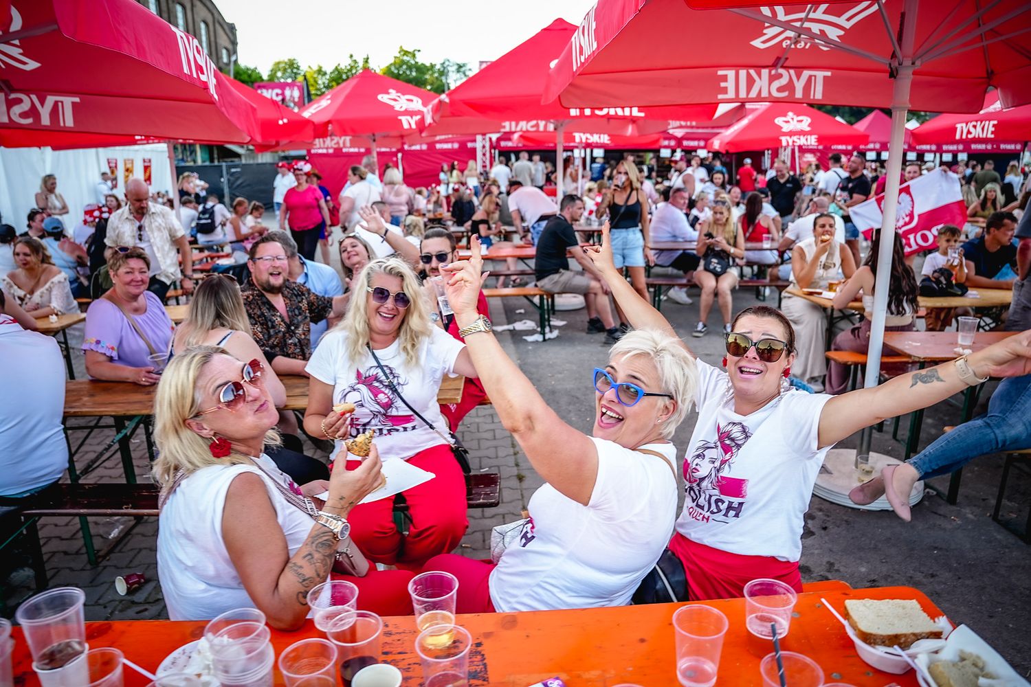 świętowanie  piwnym na świeżym powietrzu pod czerwonymi parasolami Tyskie, podnosząc kieliszki w świątecznym tłumie. Polonia music festival