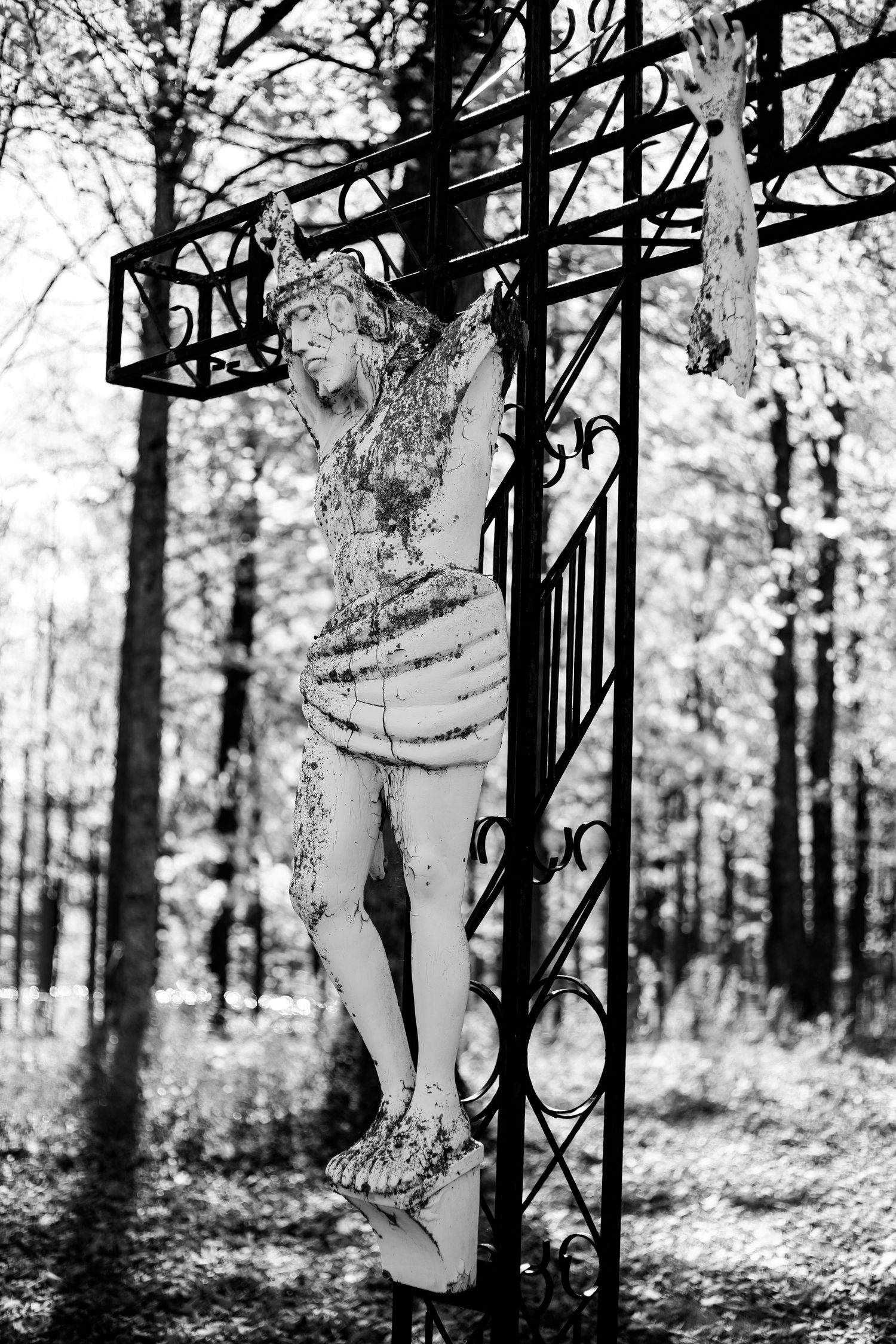 Jesus statue on the cross battered by time. Black and white.