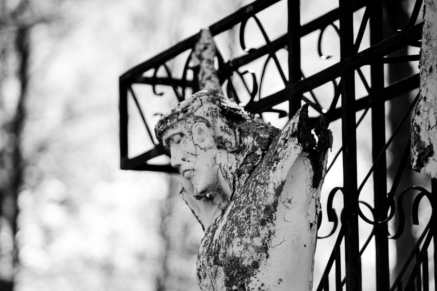 Jesus statue on the cross battered by time. Black and white.