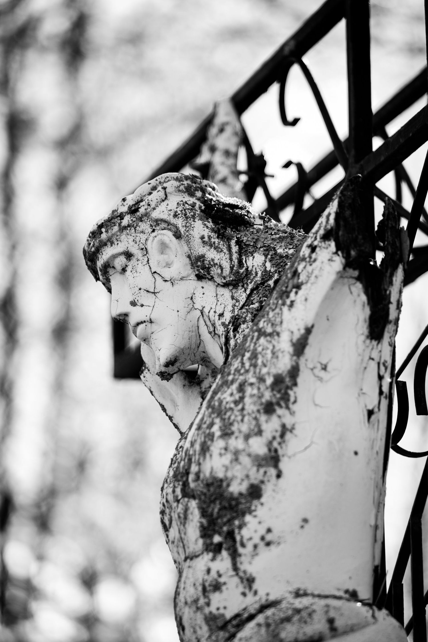 Jesus statue on the cross battered by time. Black and white.