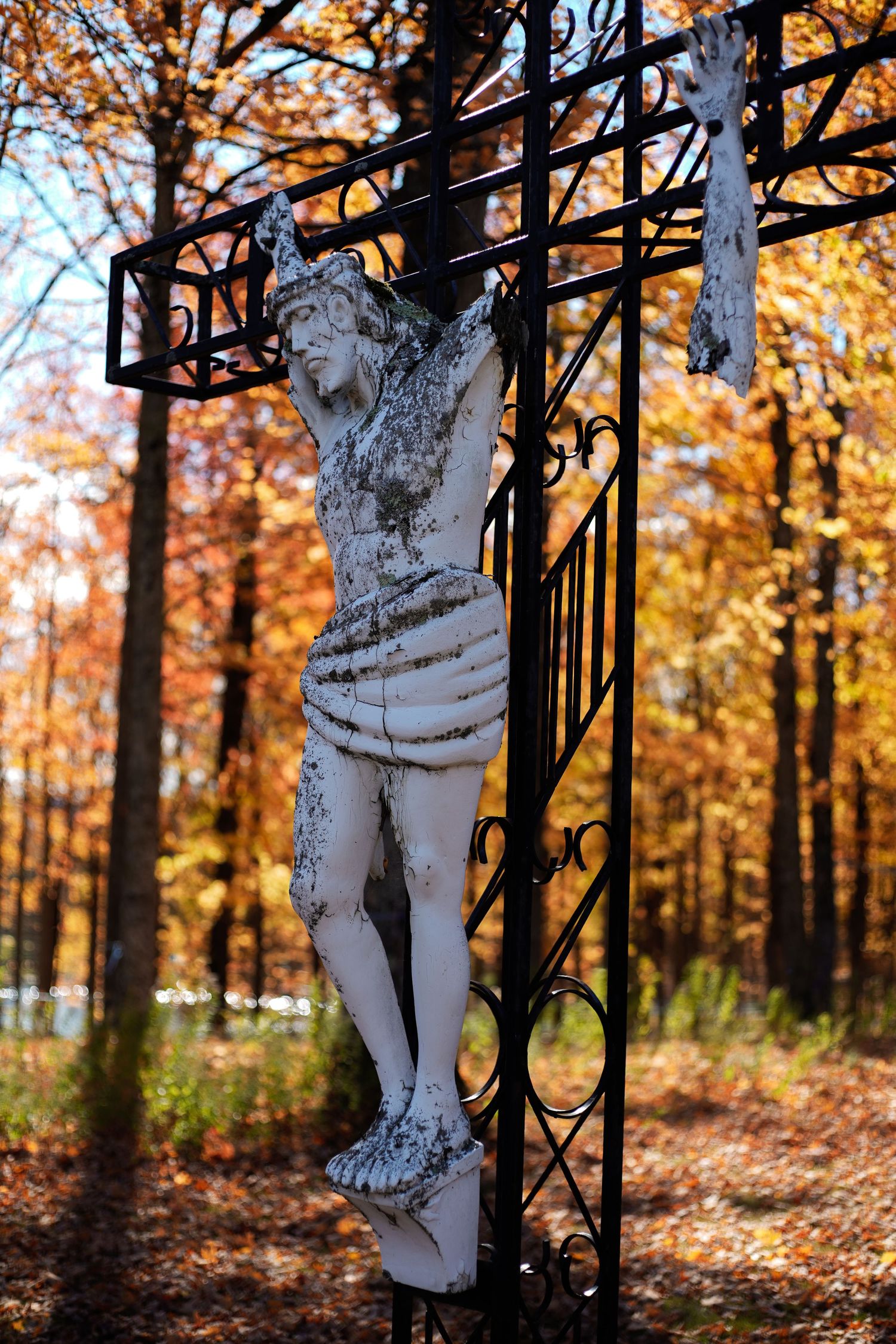 Jesus statue on the cross battered by time.