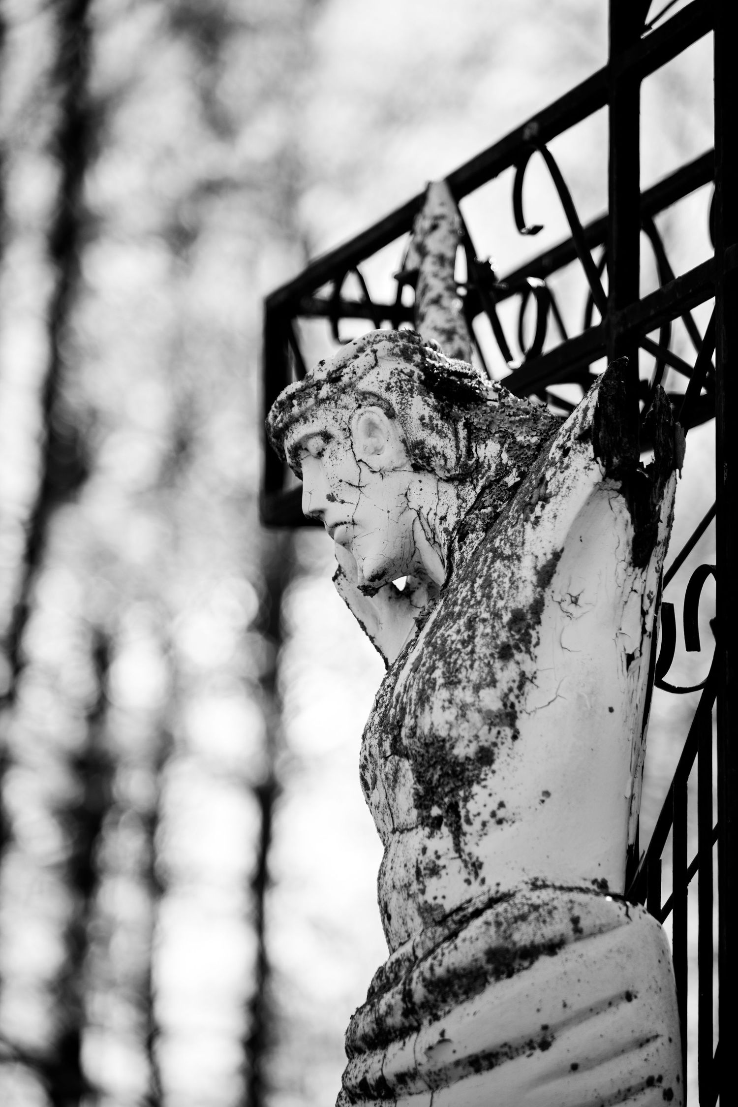 Jesus statue on the cross battered by time. Black and white.