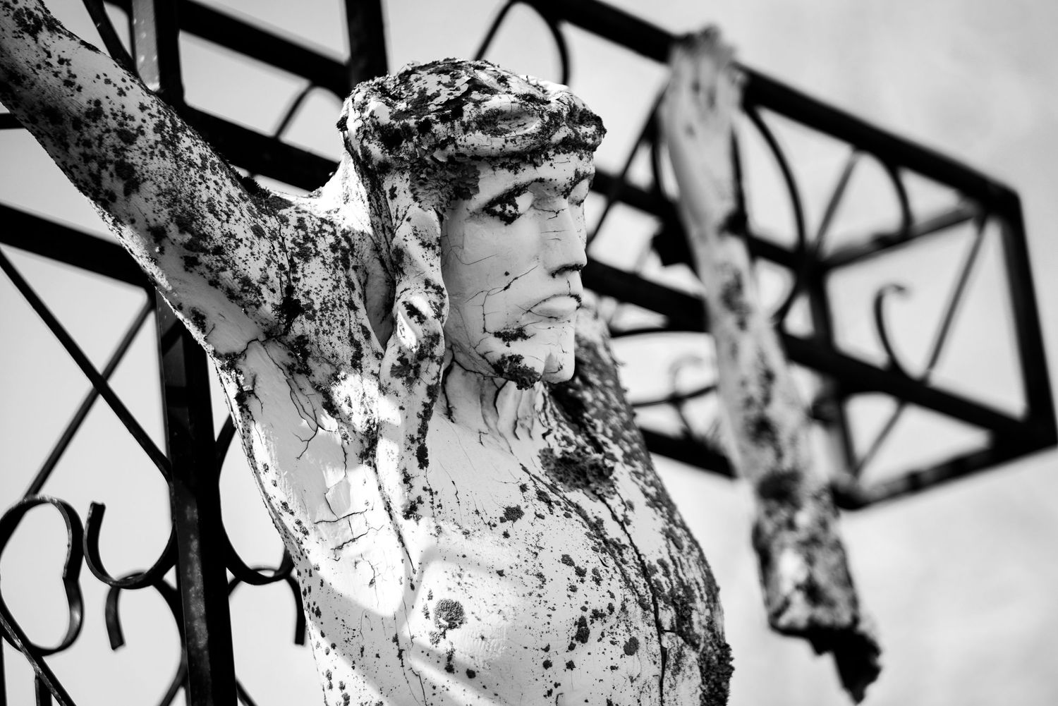 Jesus statue on the cross battered by time. Black and white.