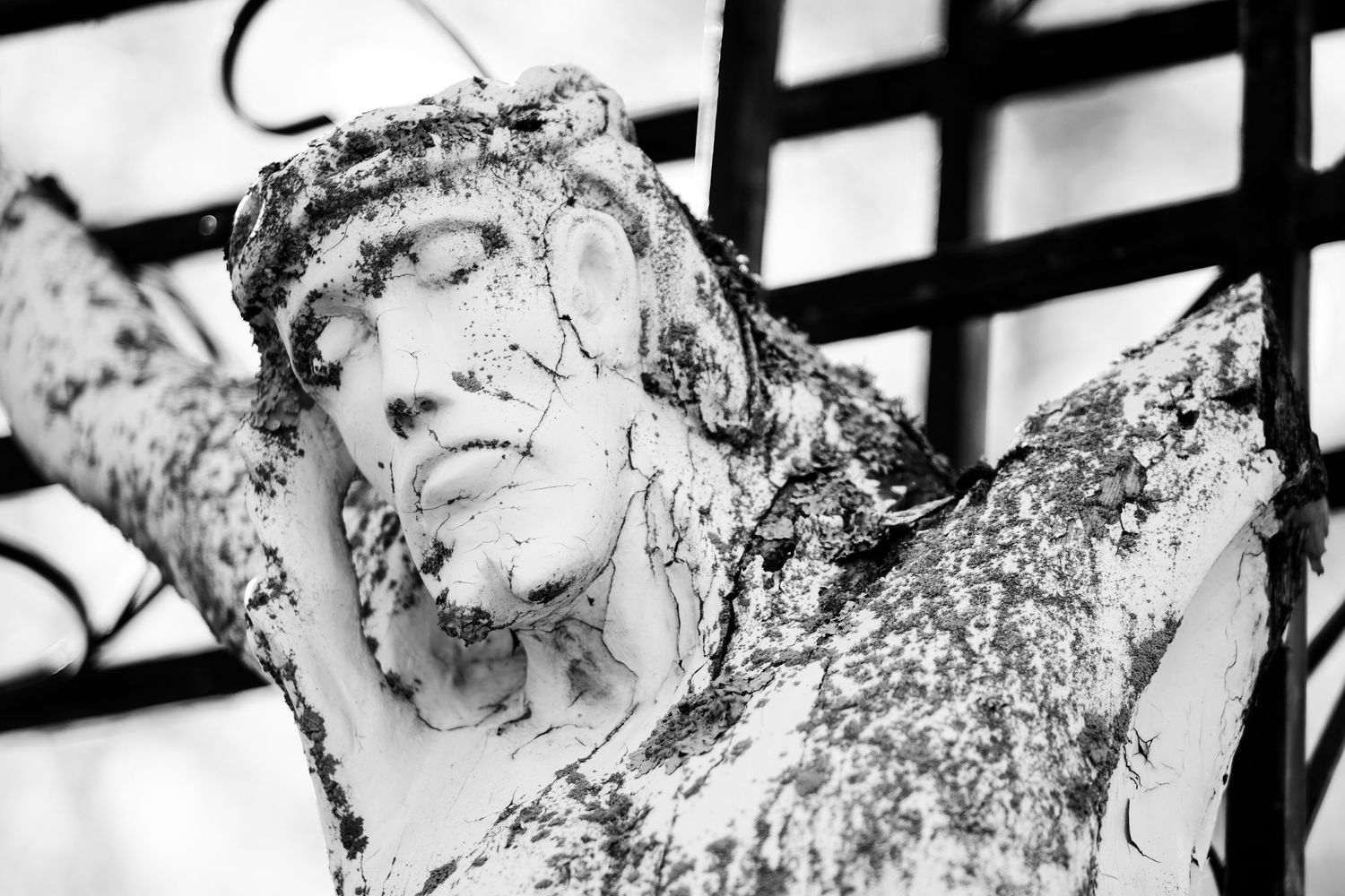 Jesus statue on the cross battered by time. Black and white.