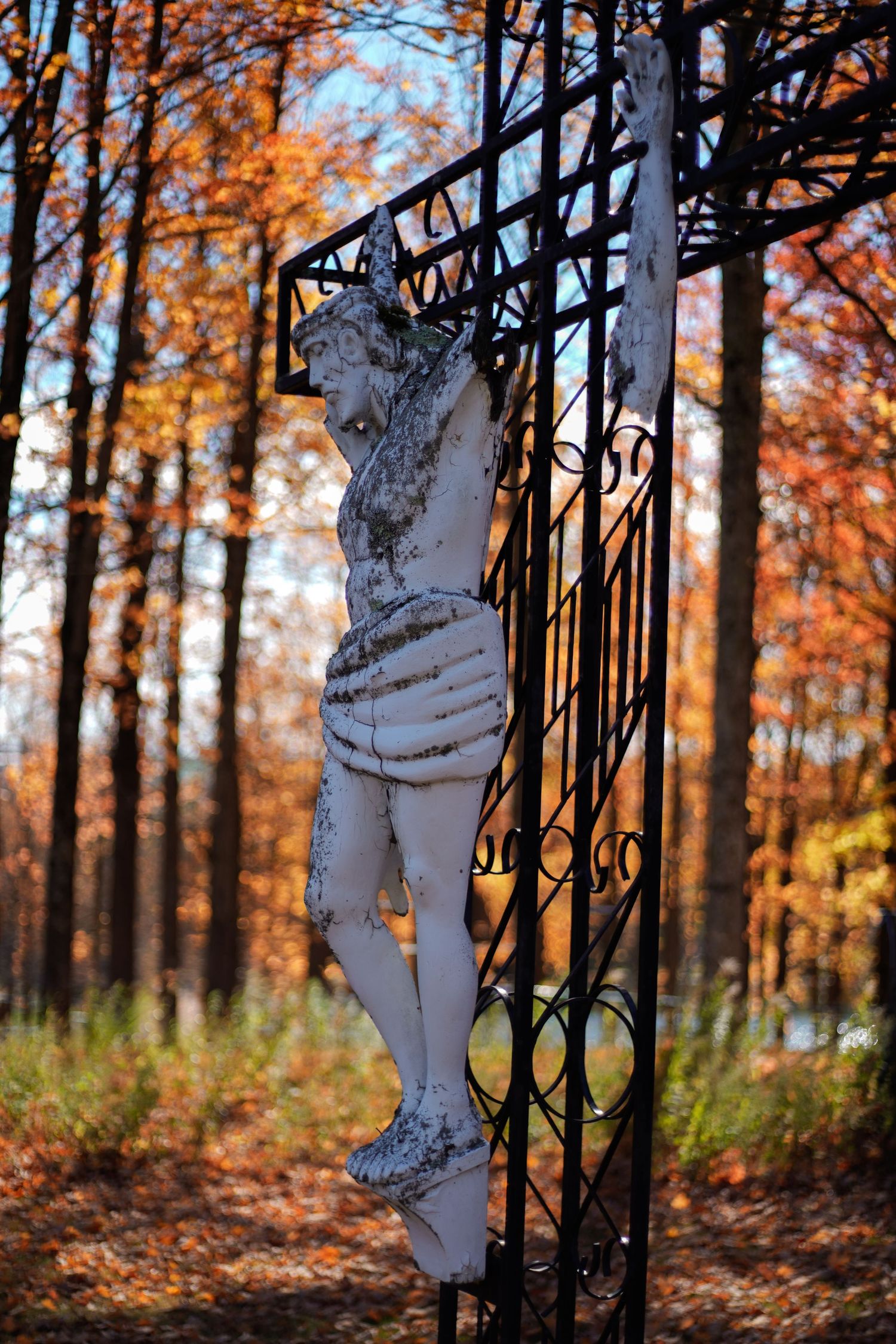 Jesus statue on the cross battered by time.