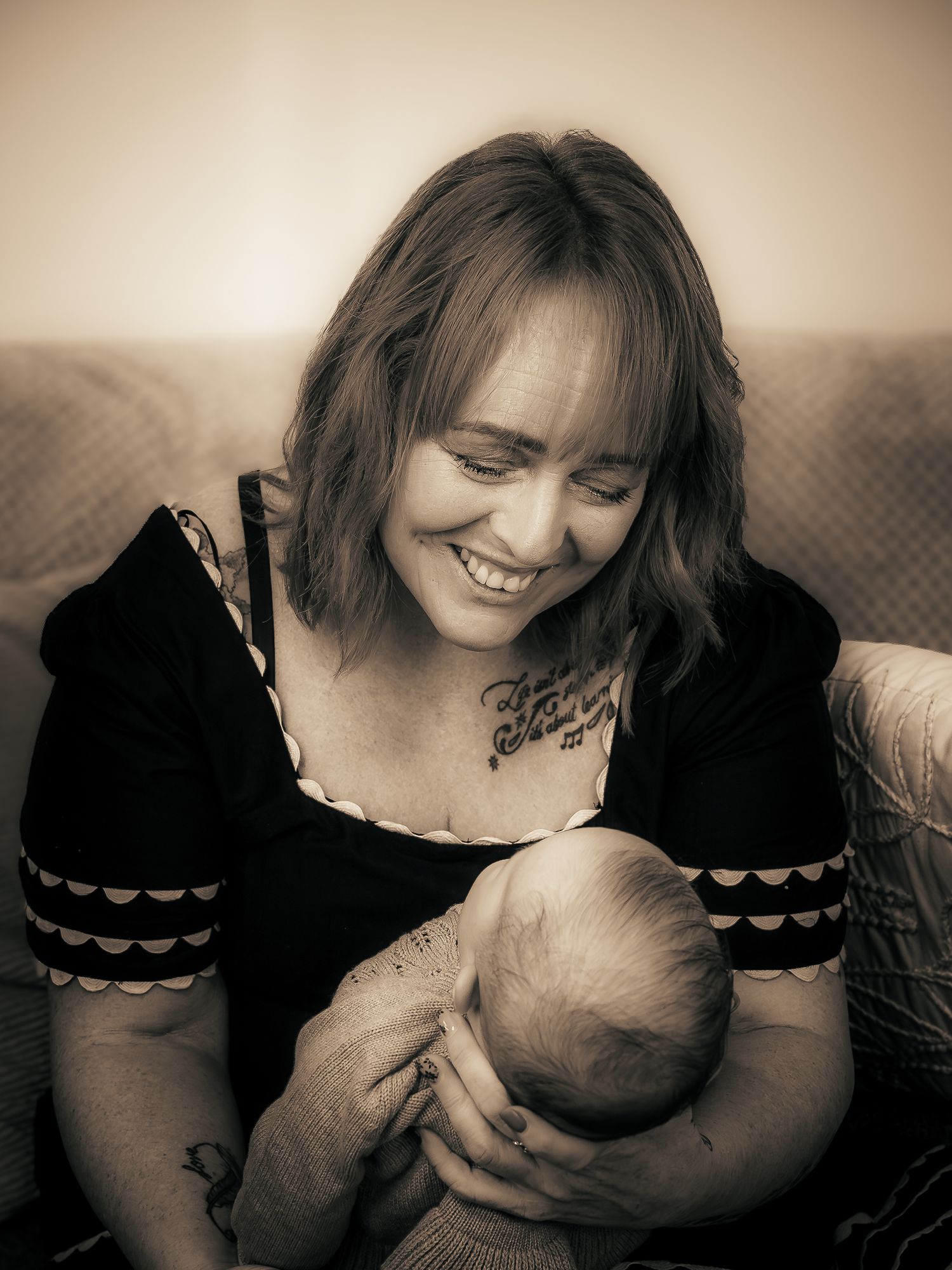 A black and white photo of a woman holding a baby close to her chest, looking down with a soft smile.