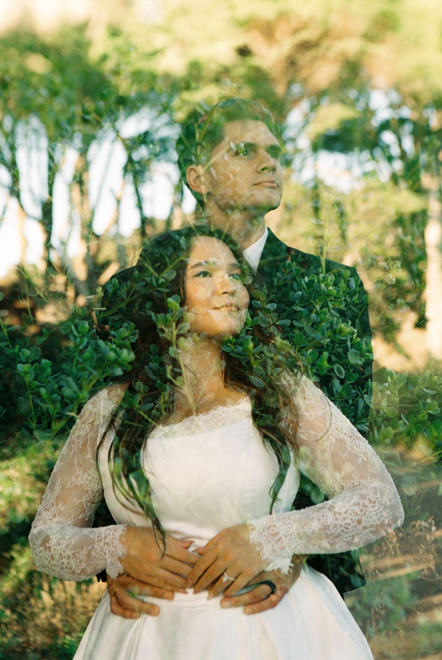Double exposure wedding photo of bride and groom embracing, blended with lush green foliage in a dreamy outdoor setting.