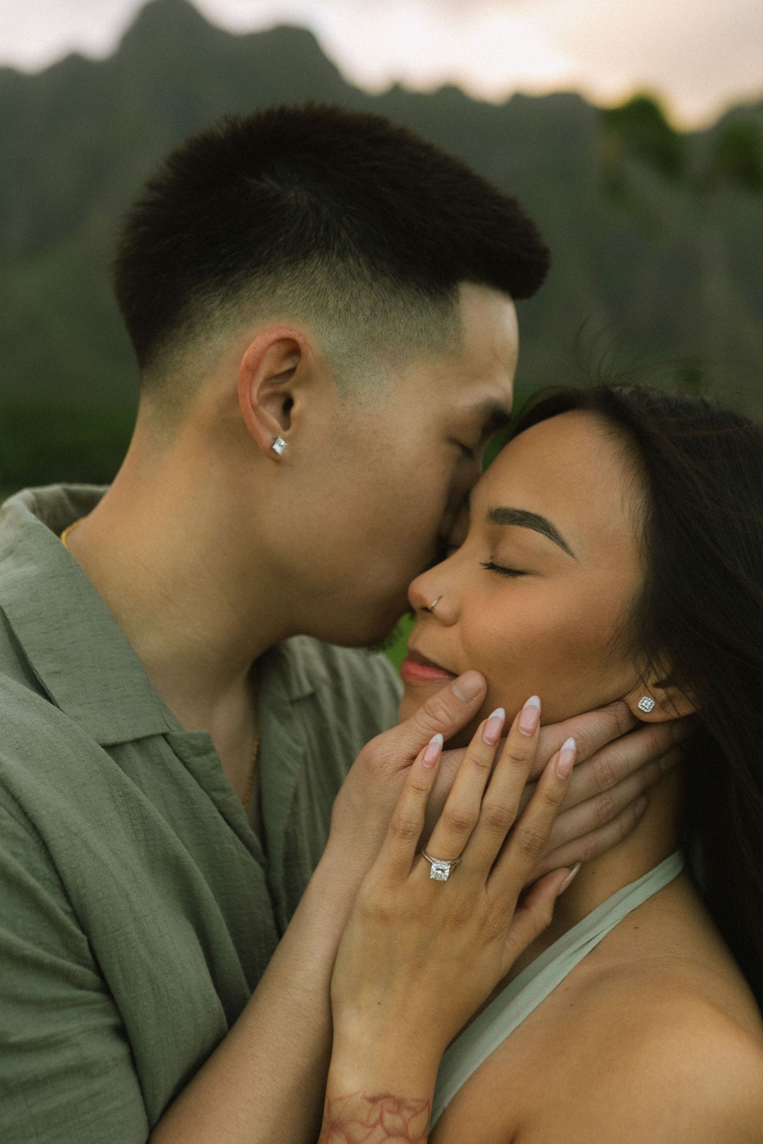 Intimate close-up of a couple sharing a tender kiss with mountain backdrop at dusk.