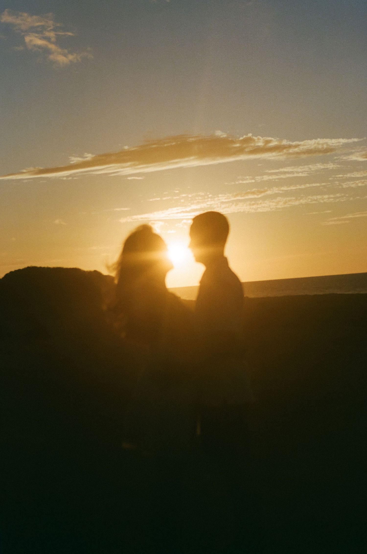 Romantic silhouette of a couple facing each other at golden sunset.