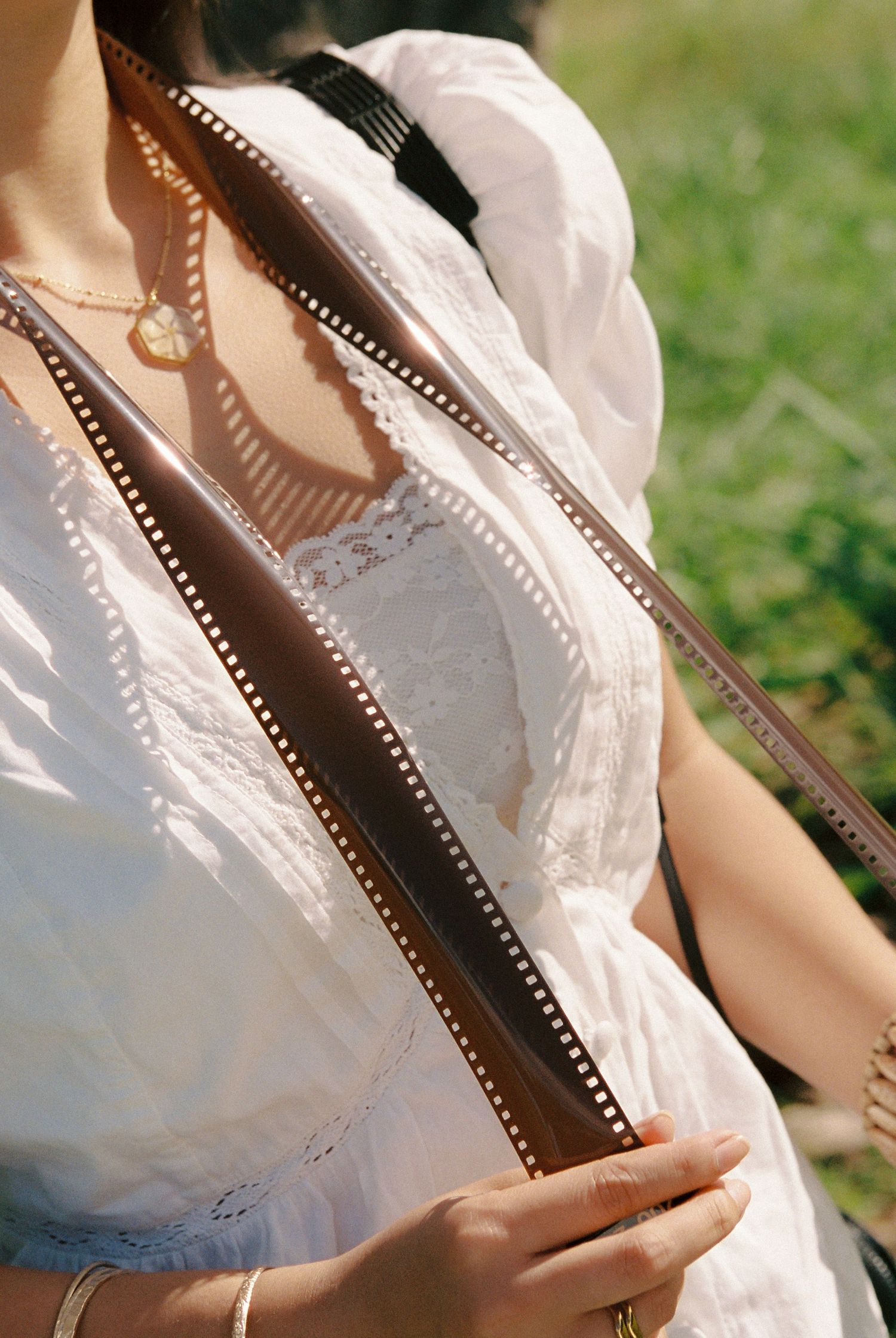 Close-up of woman in white lace dress holding a strip of photographic film negatives.