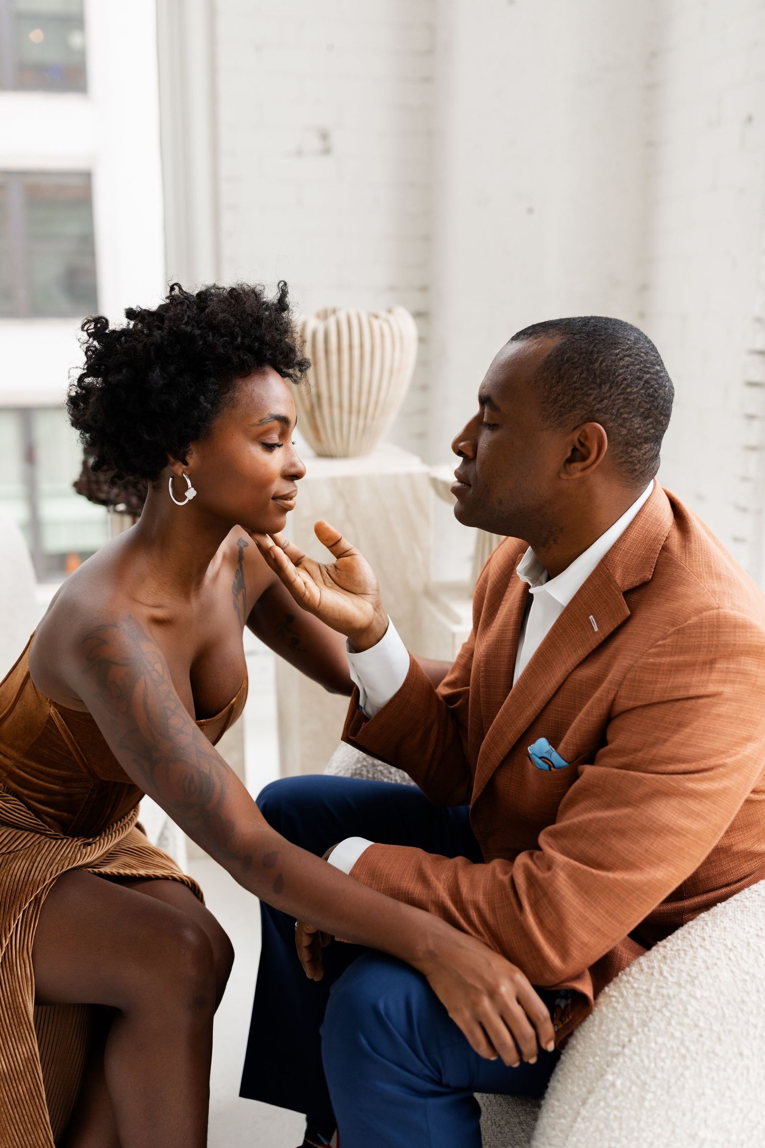Elegant couple sharing an intimate moment, man tenderly touching womans face indoors.