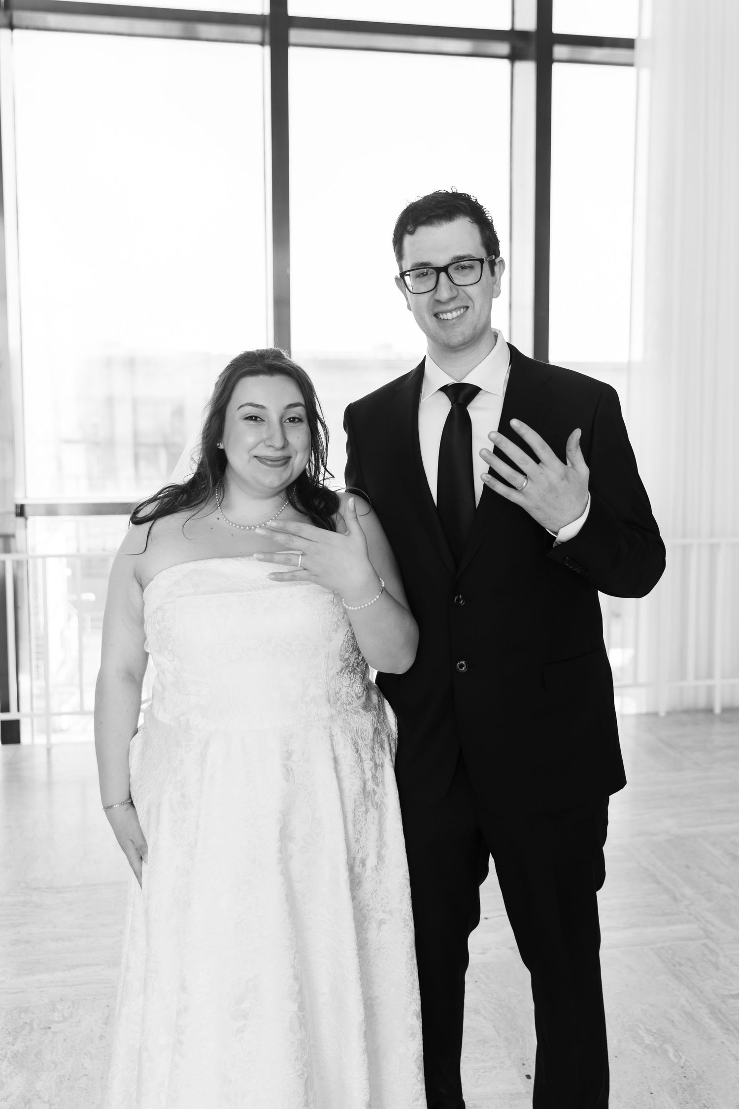 Black and white photo of smiling bride and groom posing together at their wedding reception.