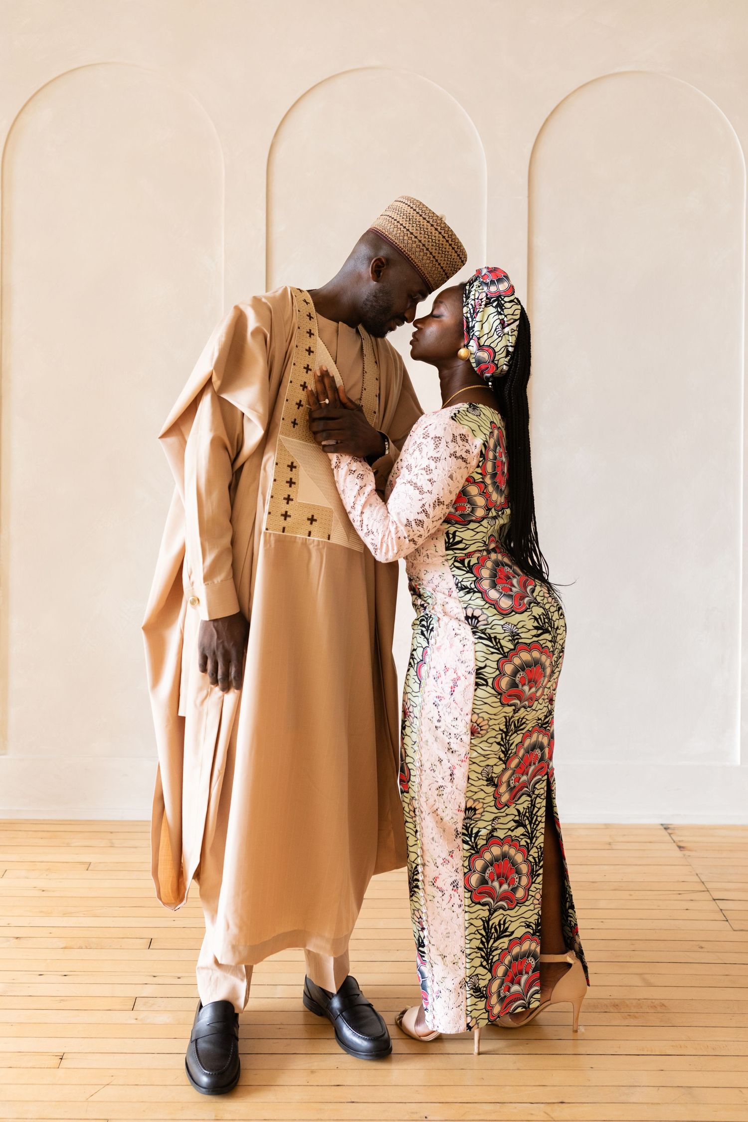 Couple in traditional attire sharing a romantic kiss in an elegant room.
