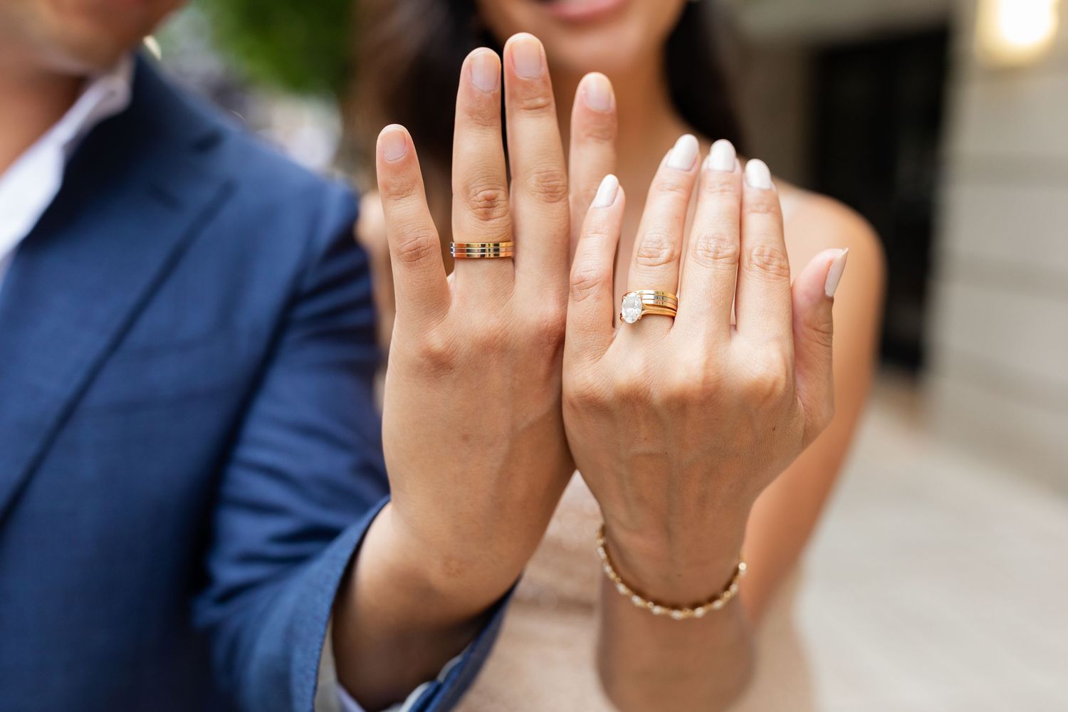 Newlywed couple showing off their wedding rings, bride wearing diamond engagement ring and gold band.
