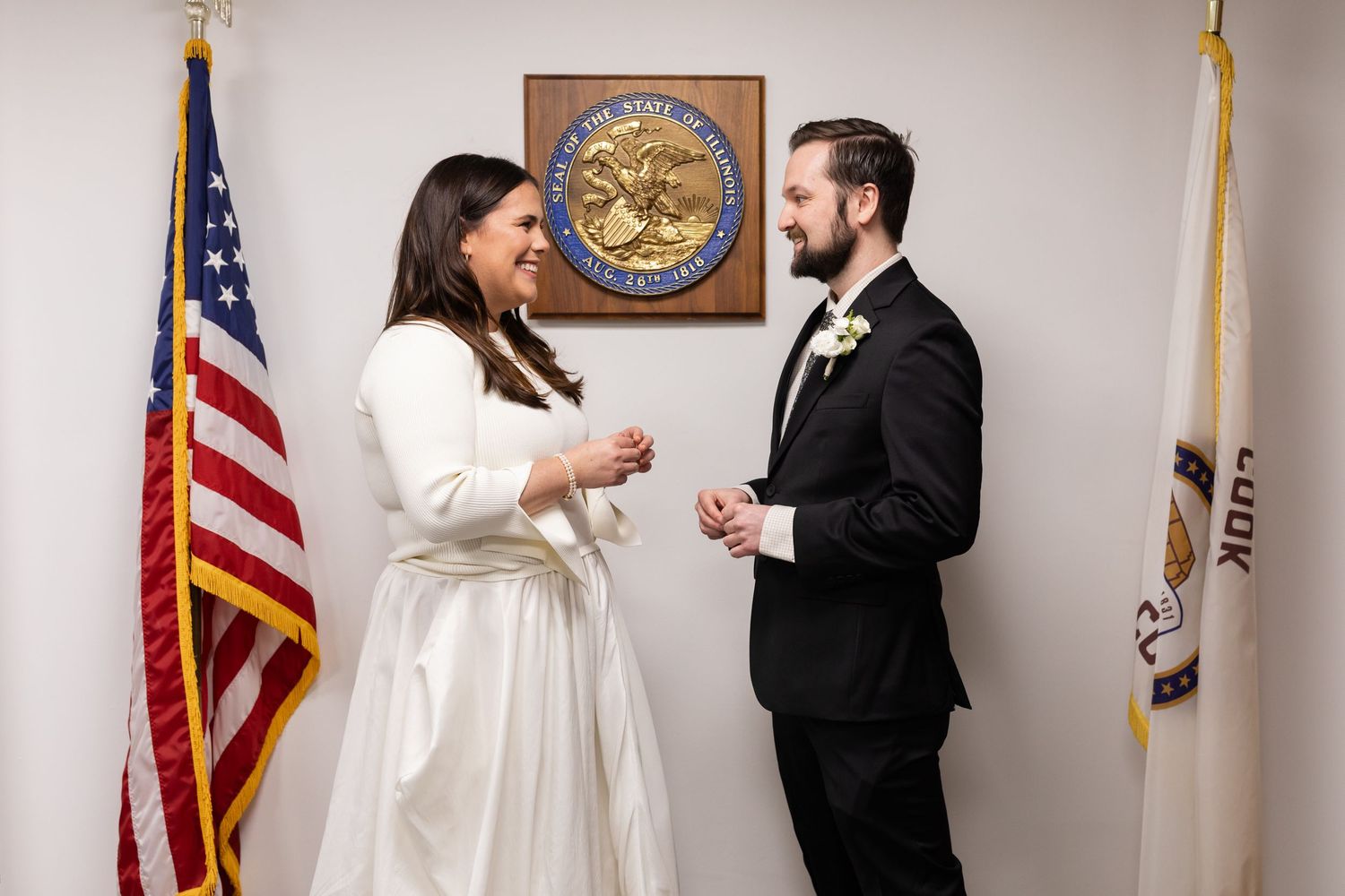 Bride and groom exchanging vows at a city hall wedding ceremony with US and Illinois state flags.