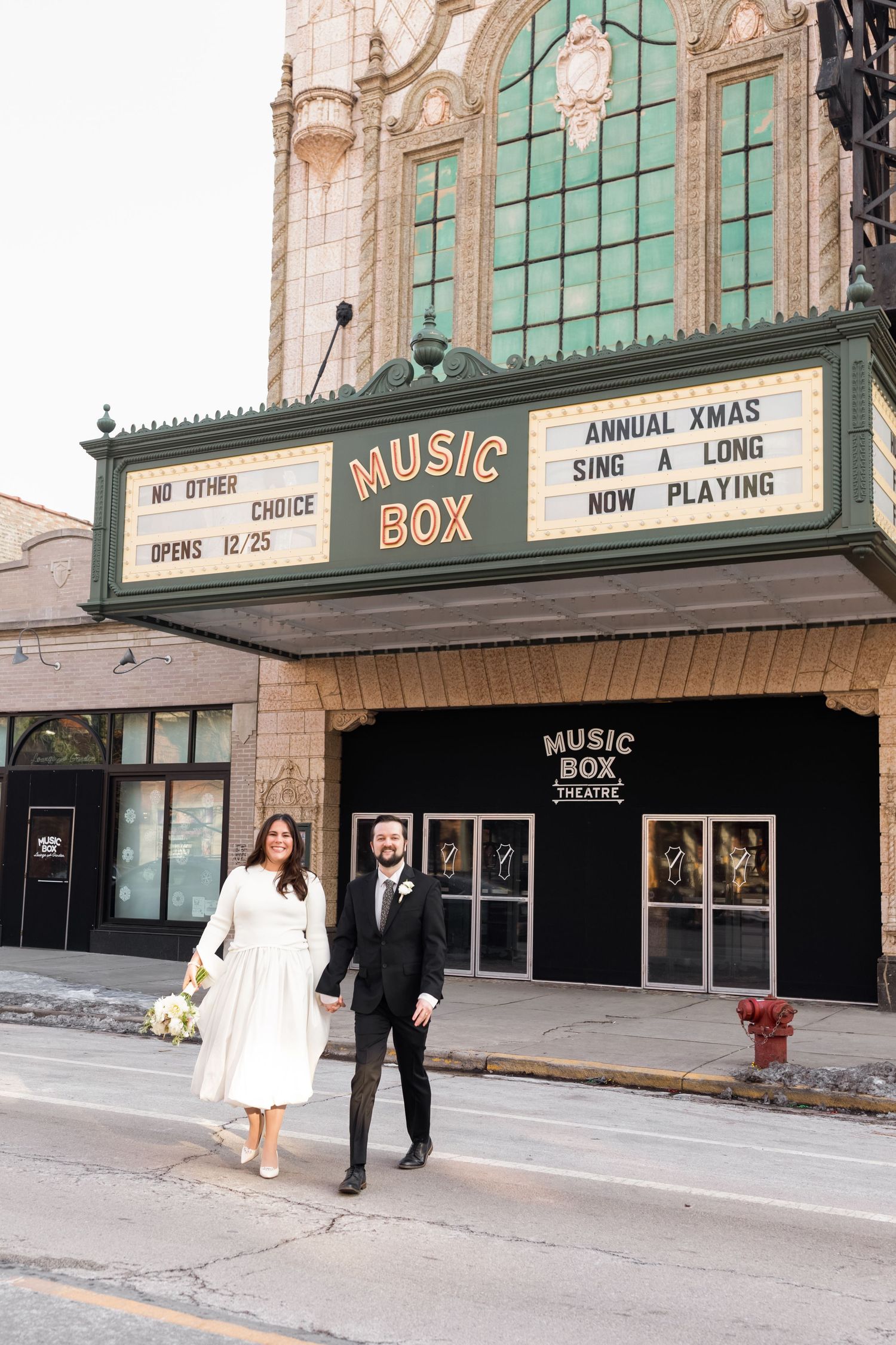 Newlyweds walk hand in hand past the iconic Music Box Theatre in Chicago.