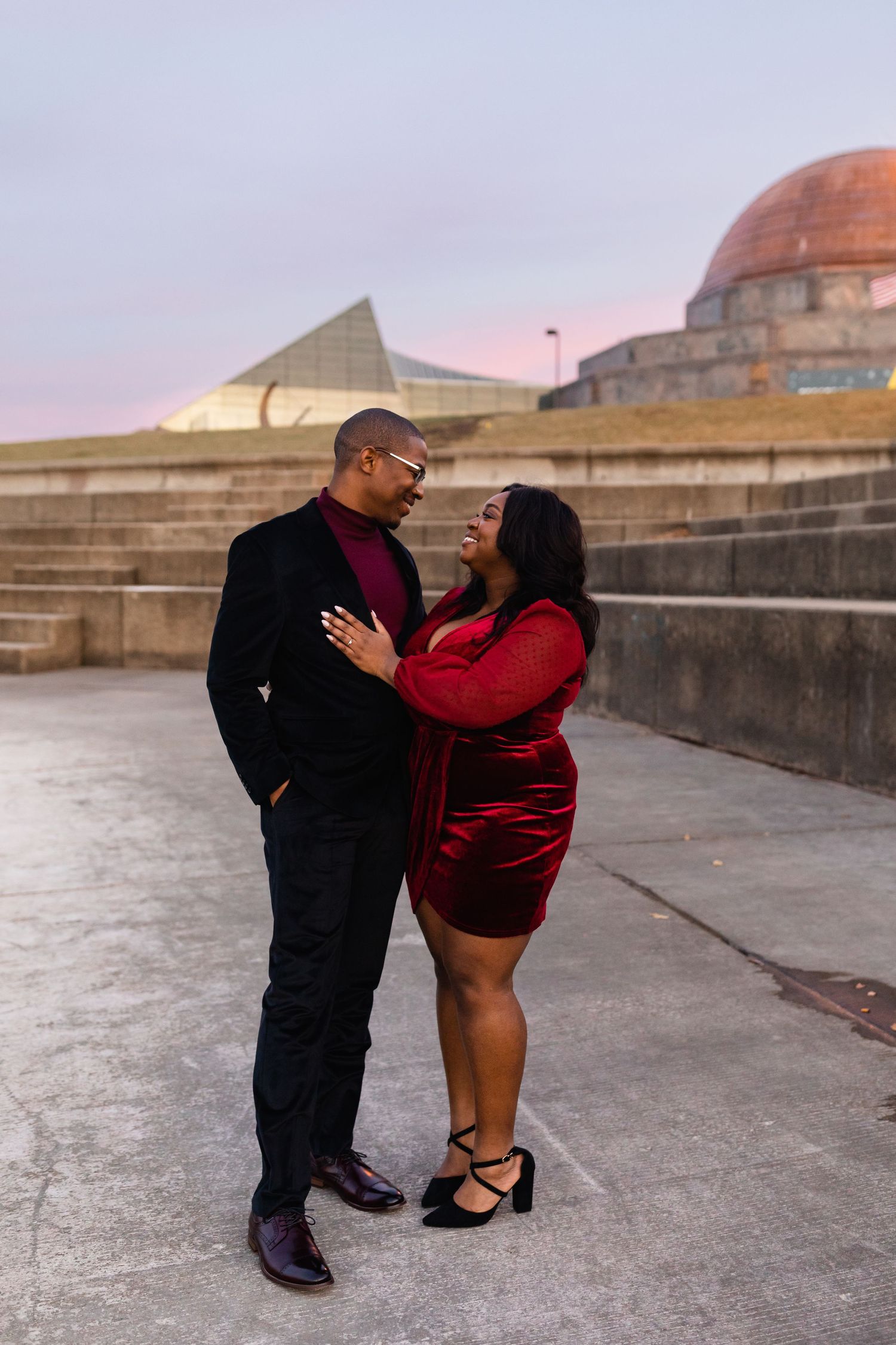 Couple in elegant attire sharing a romantic moment outside the Adler Planetarium at dusk.