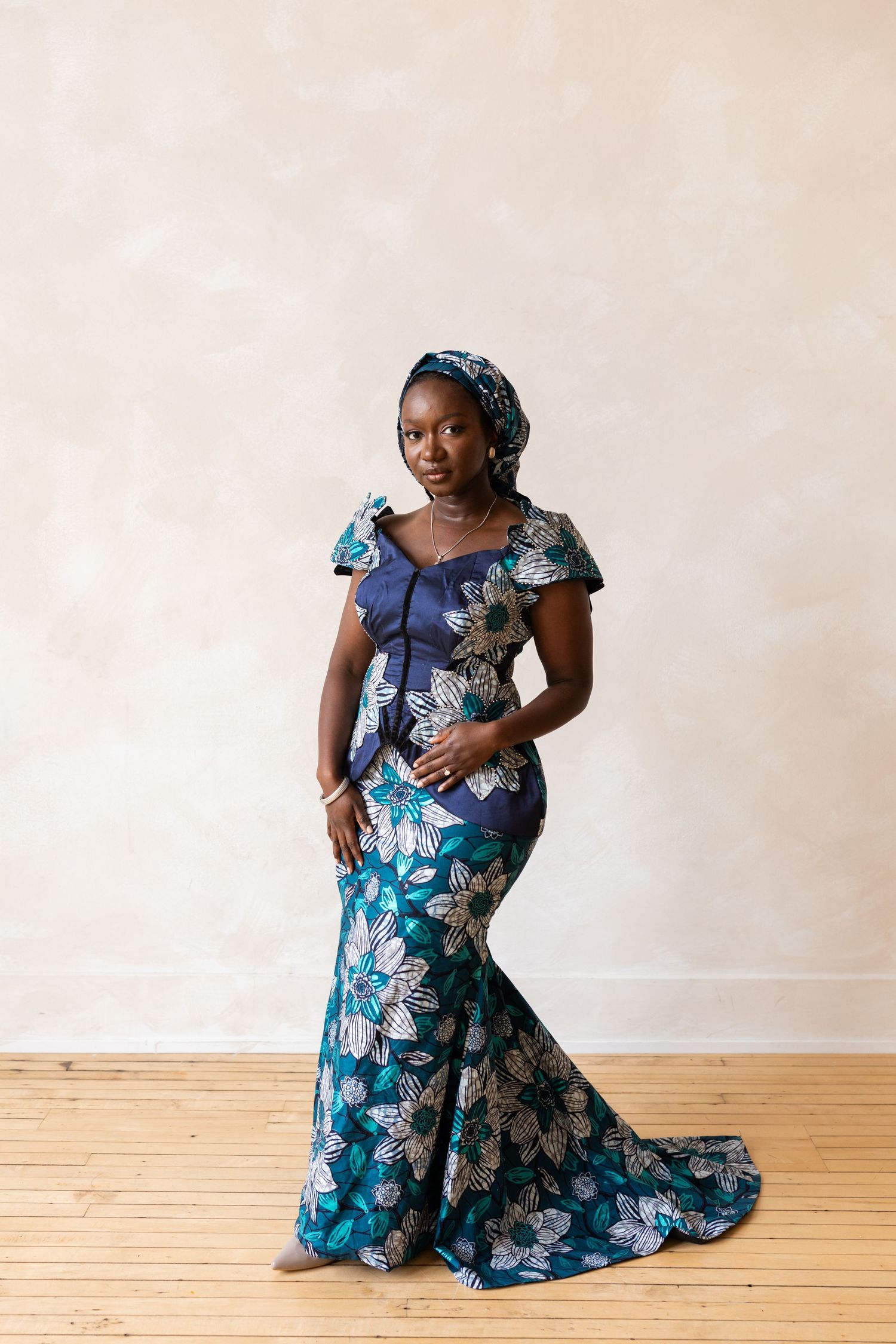 Elegant woman in a blue floral traditional mermaid dress with matching headwrap.