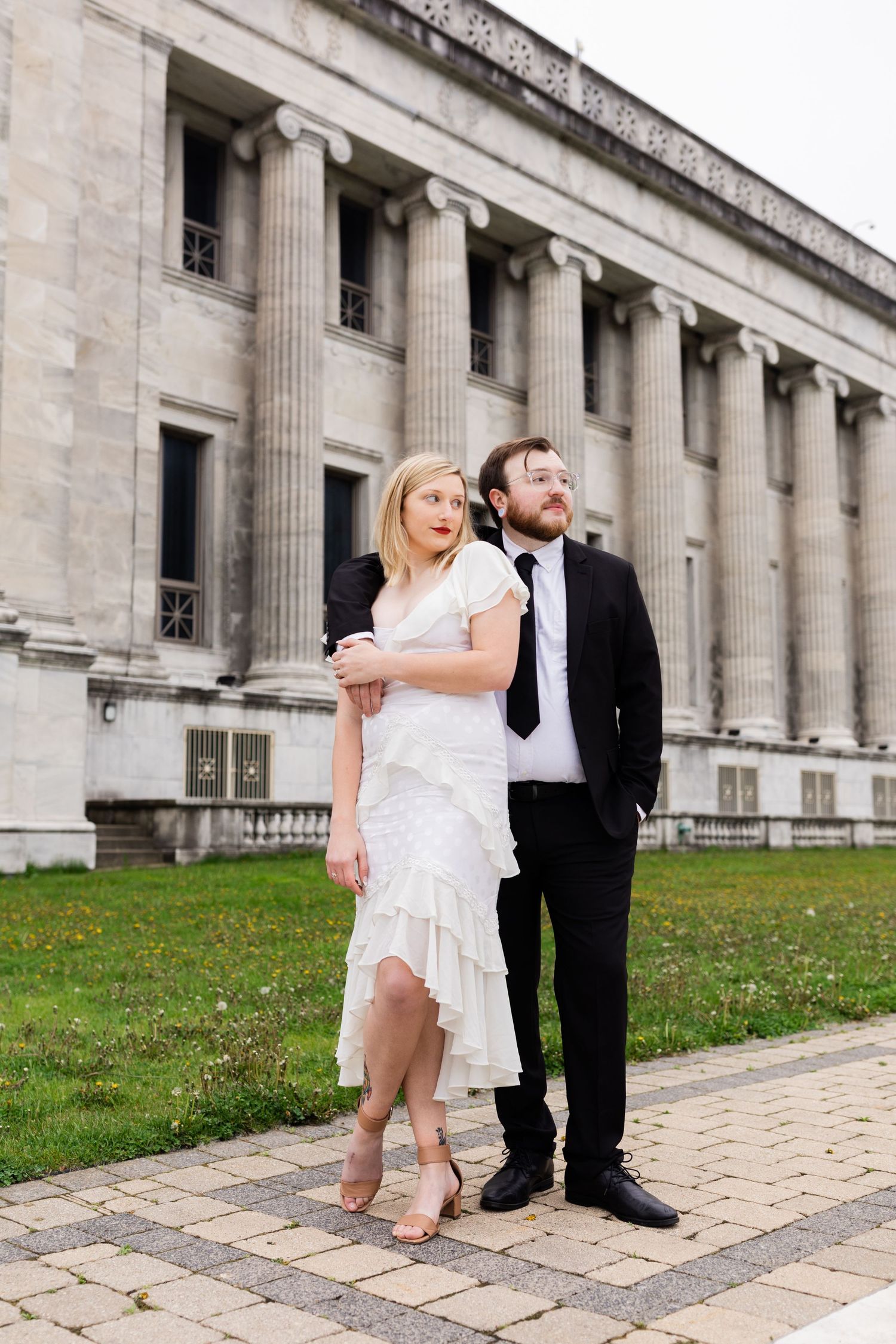 Couple in wedding attire poses before a neoclassical building with tall columns in Chicago.