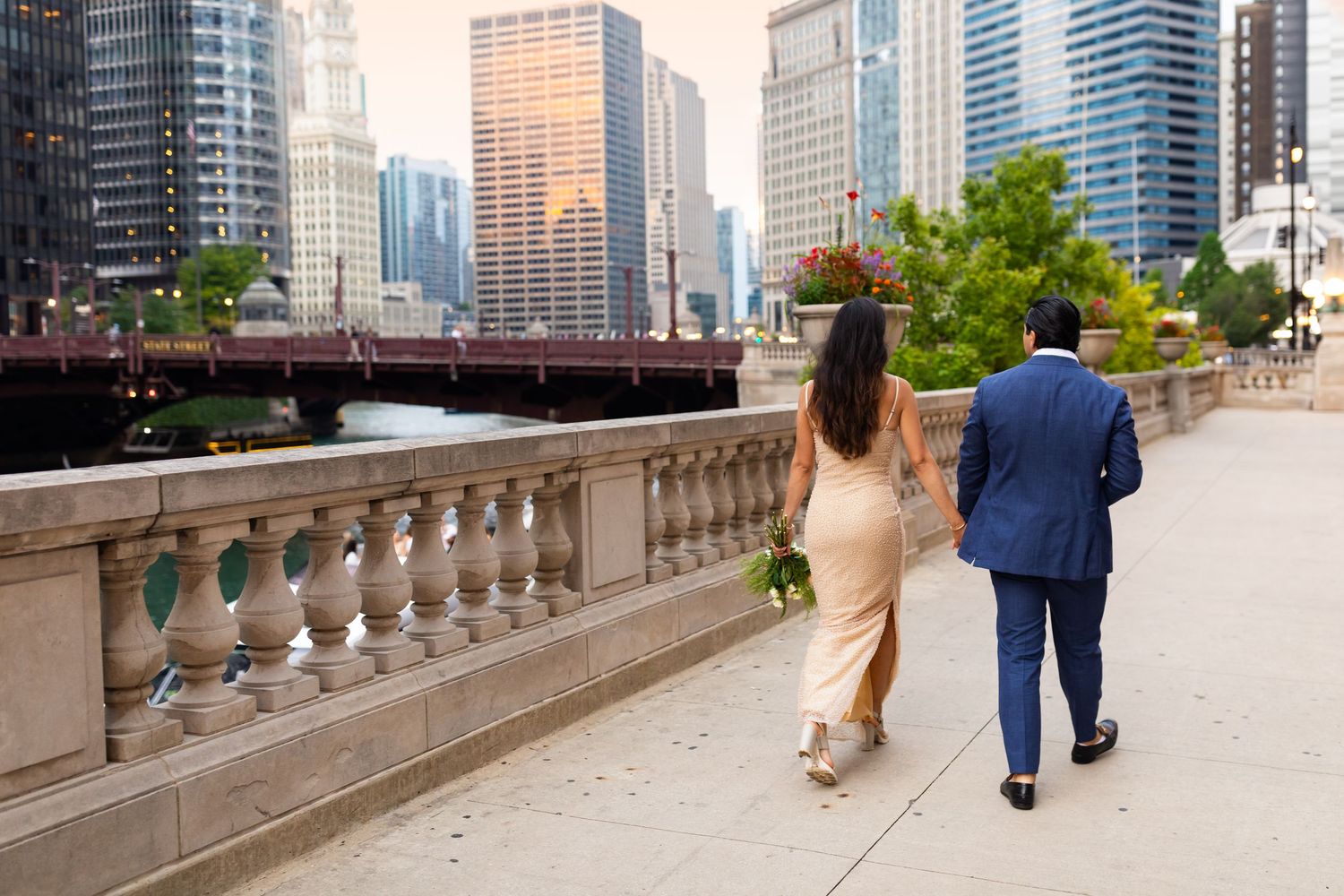 Newlywed couple strolling along Chicago Riverwalk promenade with stunning city skyline in background.