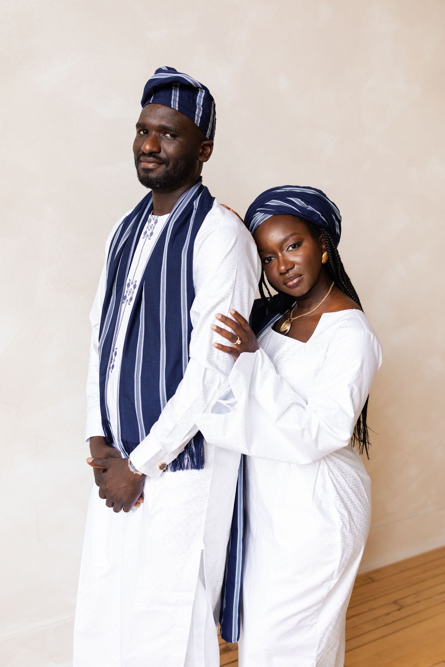 Couple in matching white and navy blue traditional outfits posing together.