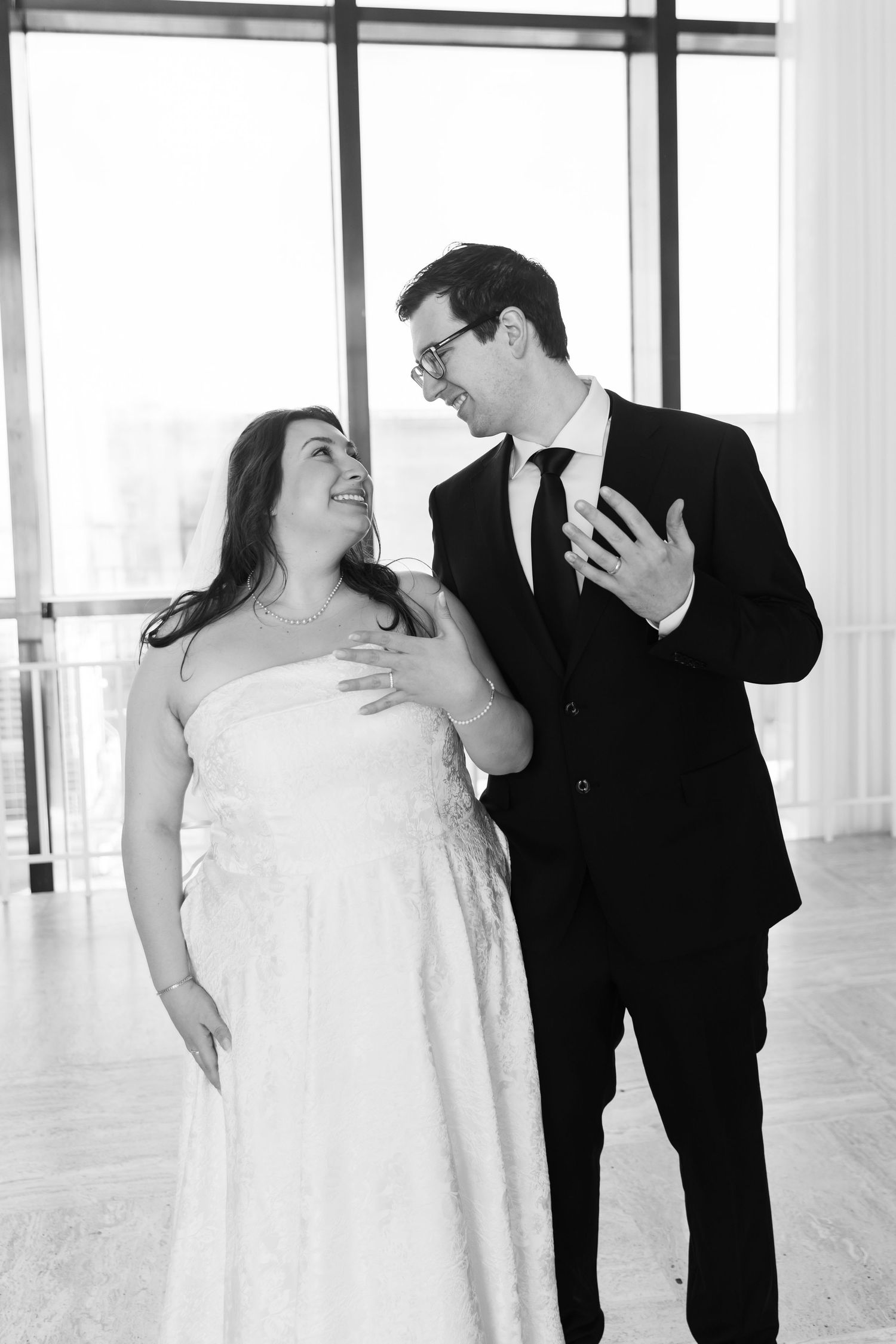 Black and white photo of smiling bride and groom sharing a joyful moment together on their wedding day.