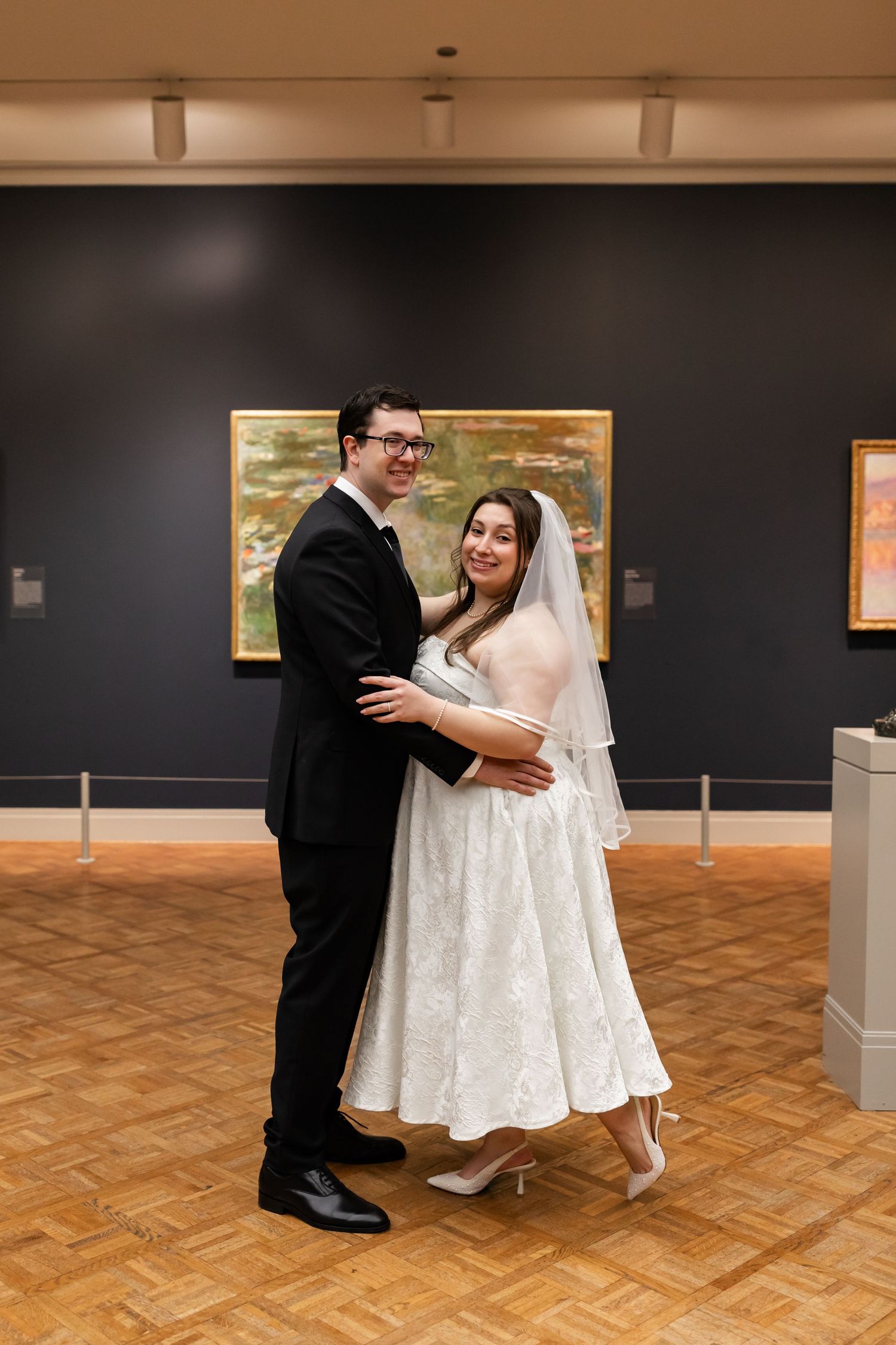 Bride and groom dancing together in a wedding portrait inside an art museum gallery with impressionist paintings.
