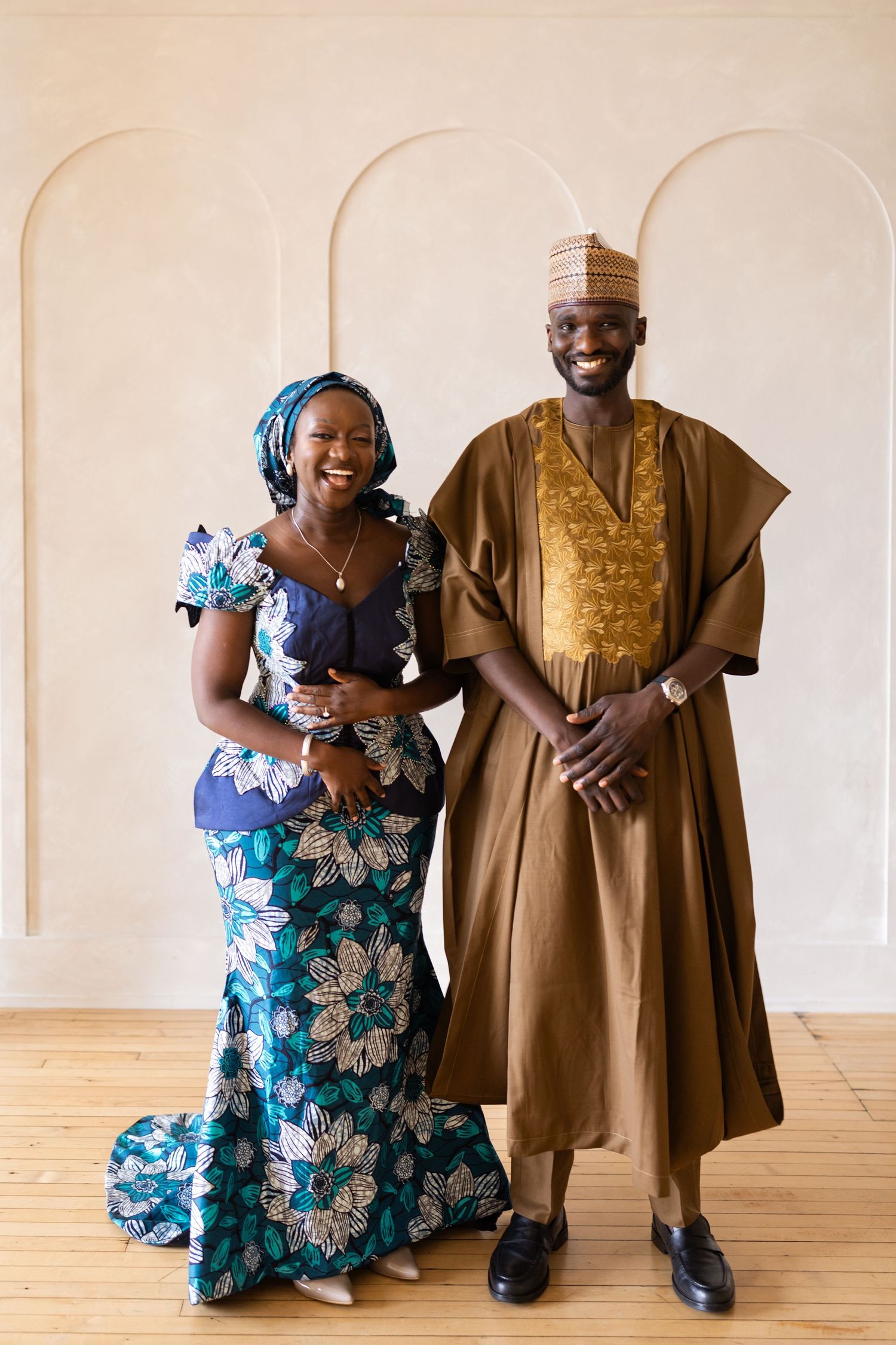 Joyfu couple in traditional attire smiling together in a bright elegant room.