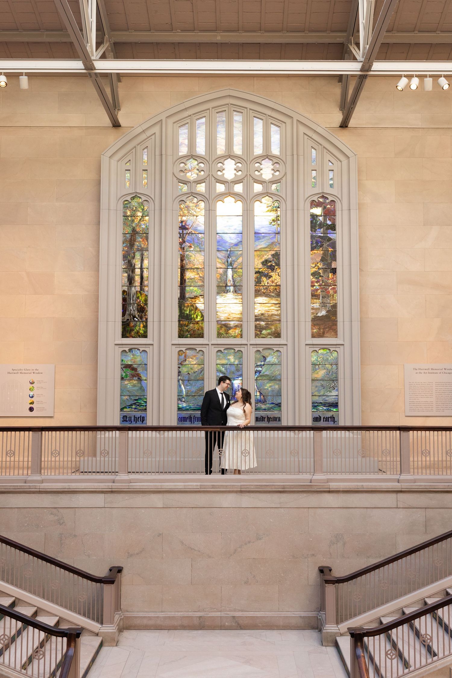 Couple shares intimate moment before stunning stained glass window inside elegant museum gallery.