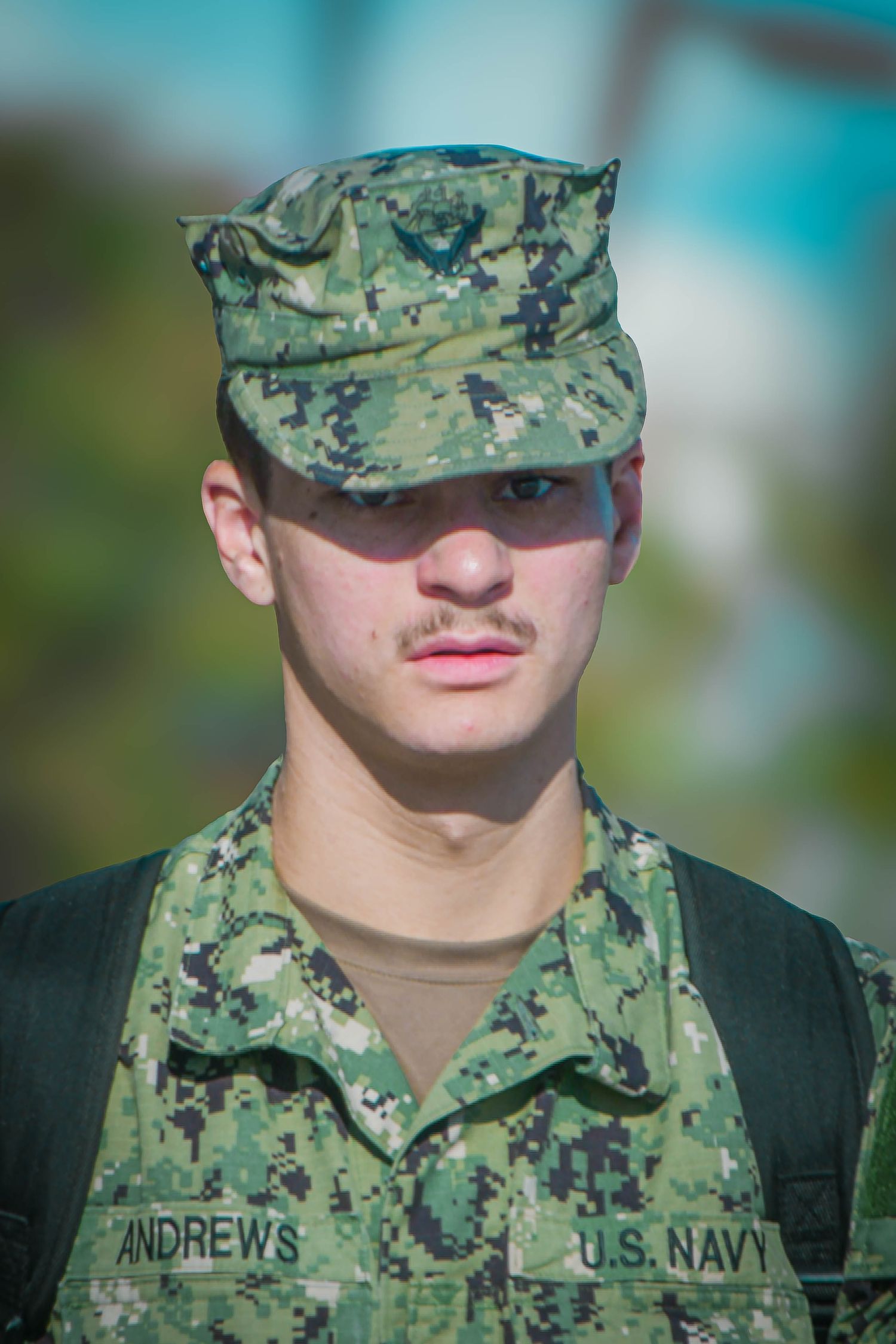 U.S. Navy sailor Andrews in digital camouflage uniform and cap standing at attention outdoors.