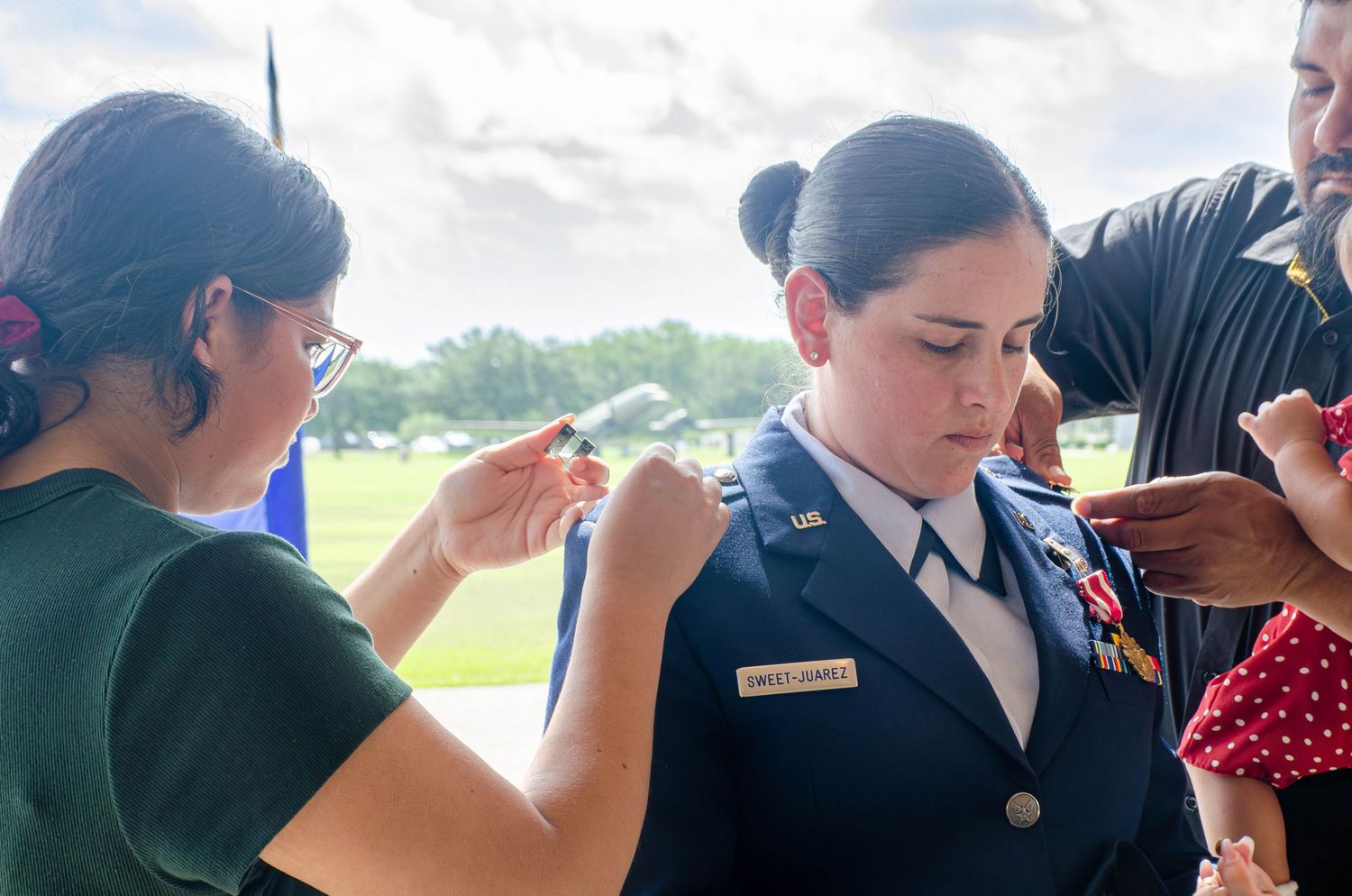 Female US Air Force officer having military insignia pinned to her uniform during a ceremony.