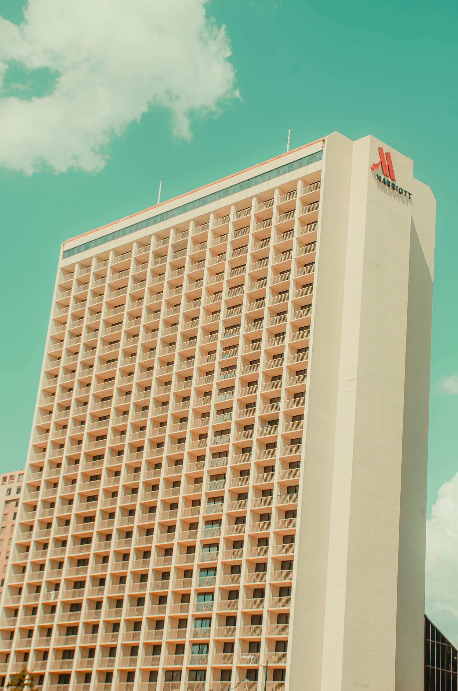 Tall Marriott hotel building with rows of balconies under a blue sky.