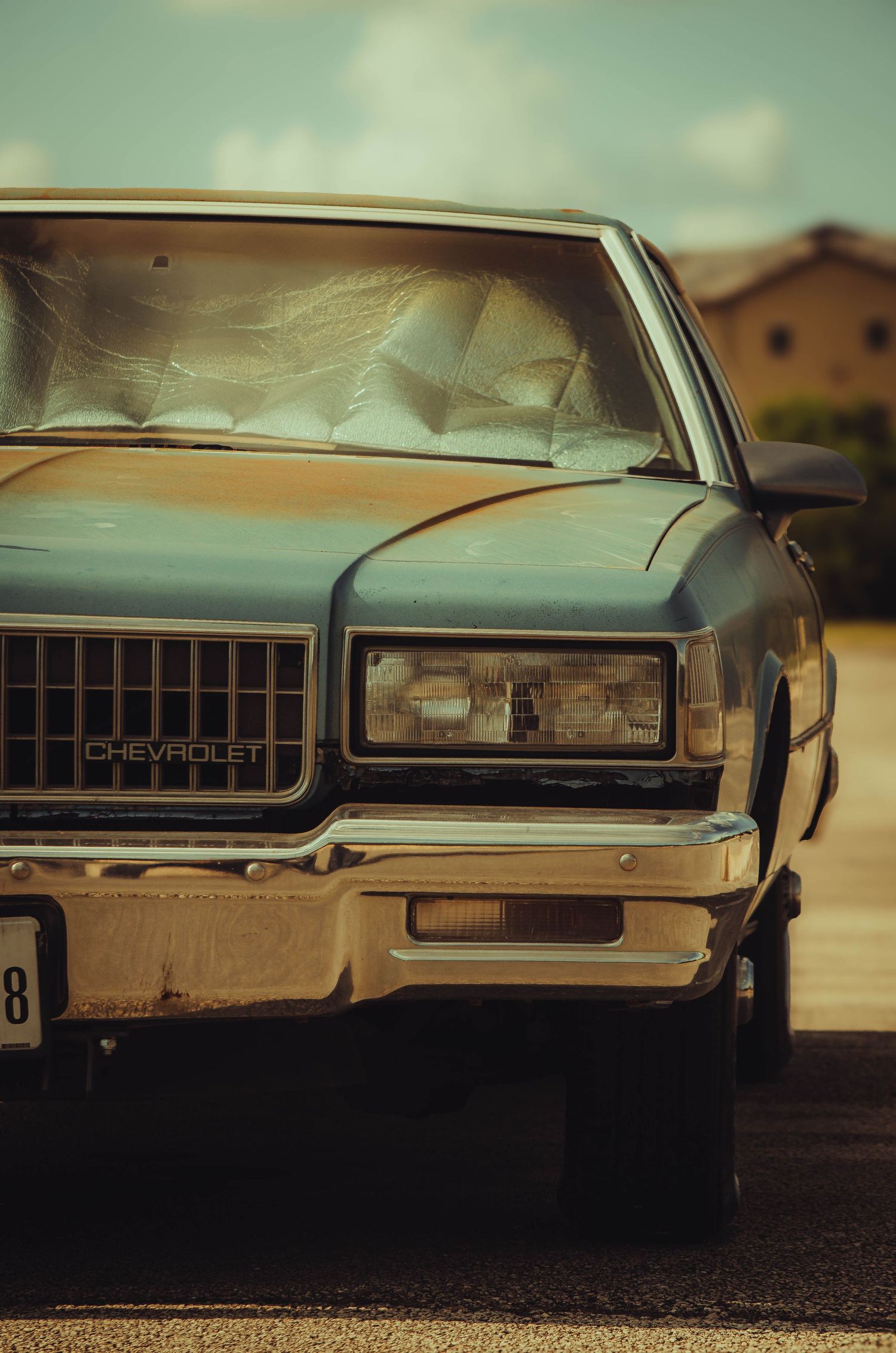 Vintage Chevrolet classic car with sun shade in windshield parked outdoors on a sunny day.