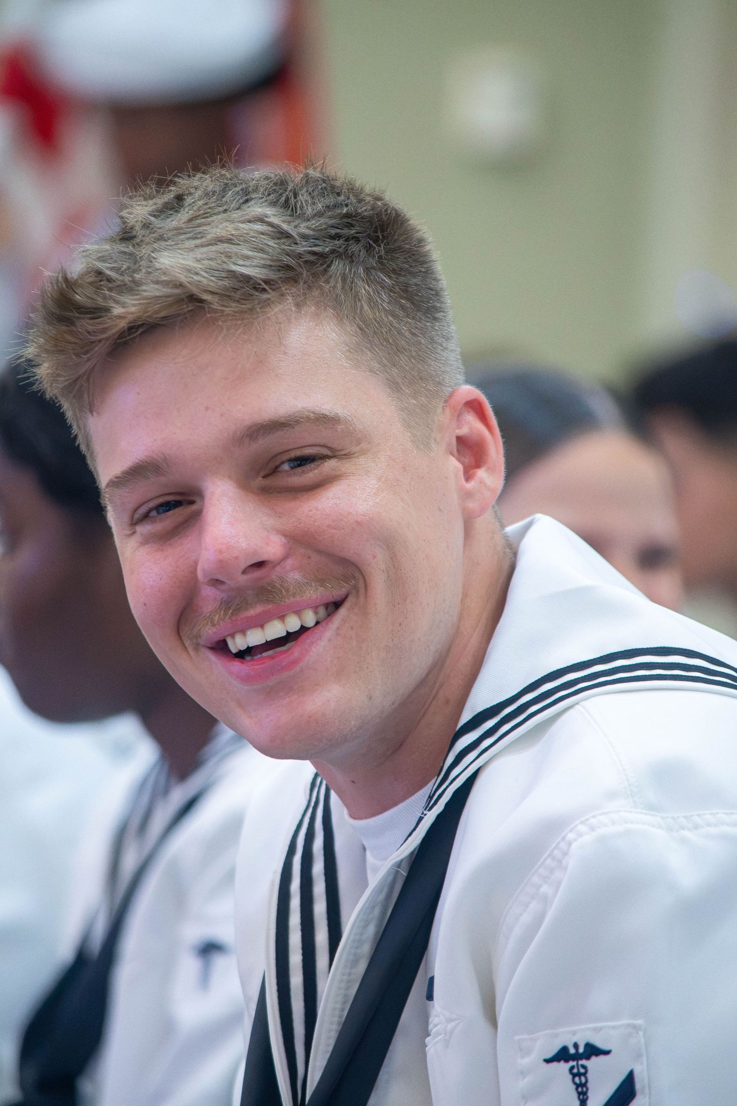 Happy young US Navy sailor with medical insignia smiling in white dress uniform.